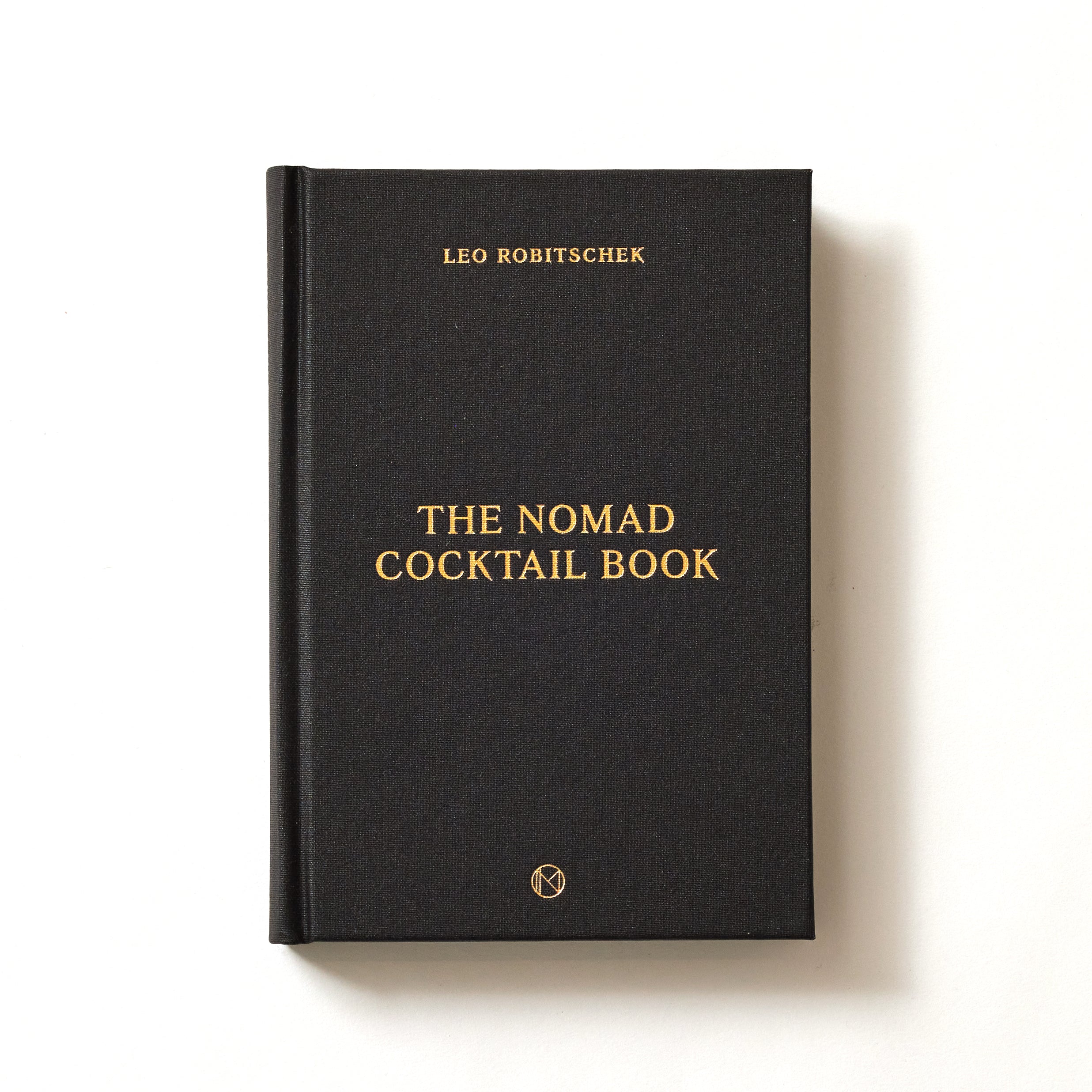 Black hardcover book titled 'The Nomad Cocktail Book' by Leo Robitschek