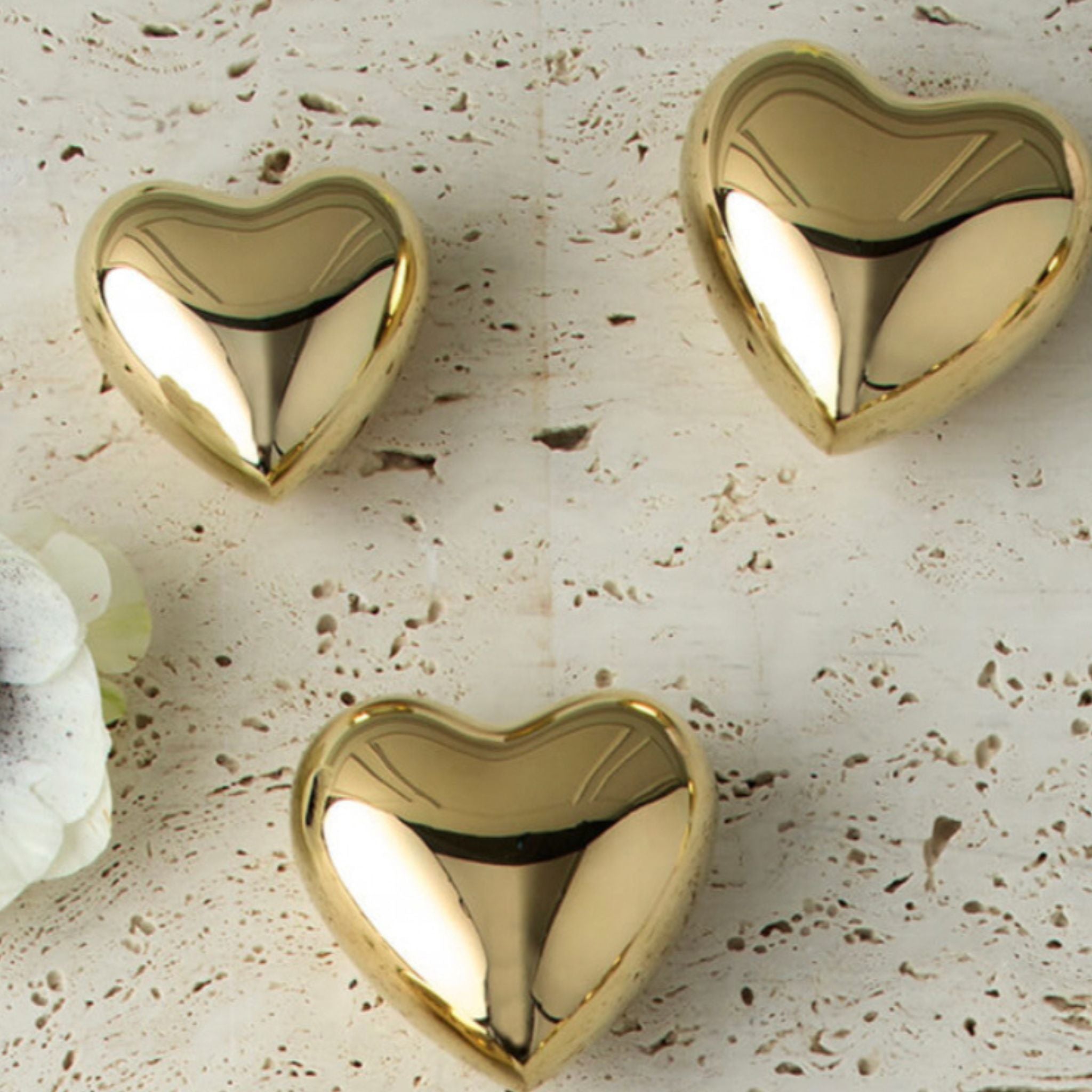 three brass heart shaped objects on a stone surface