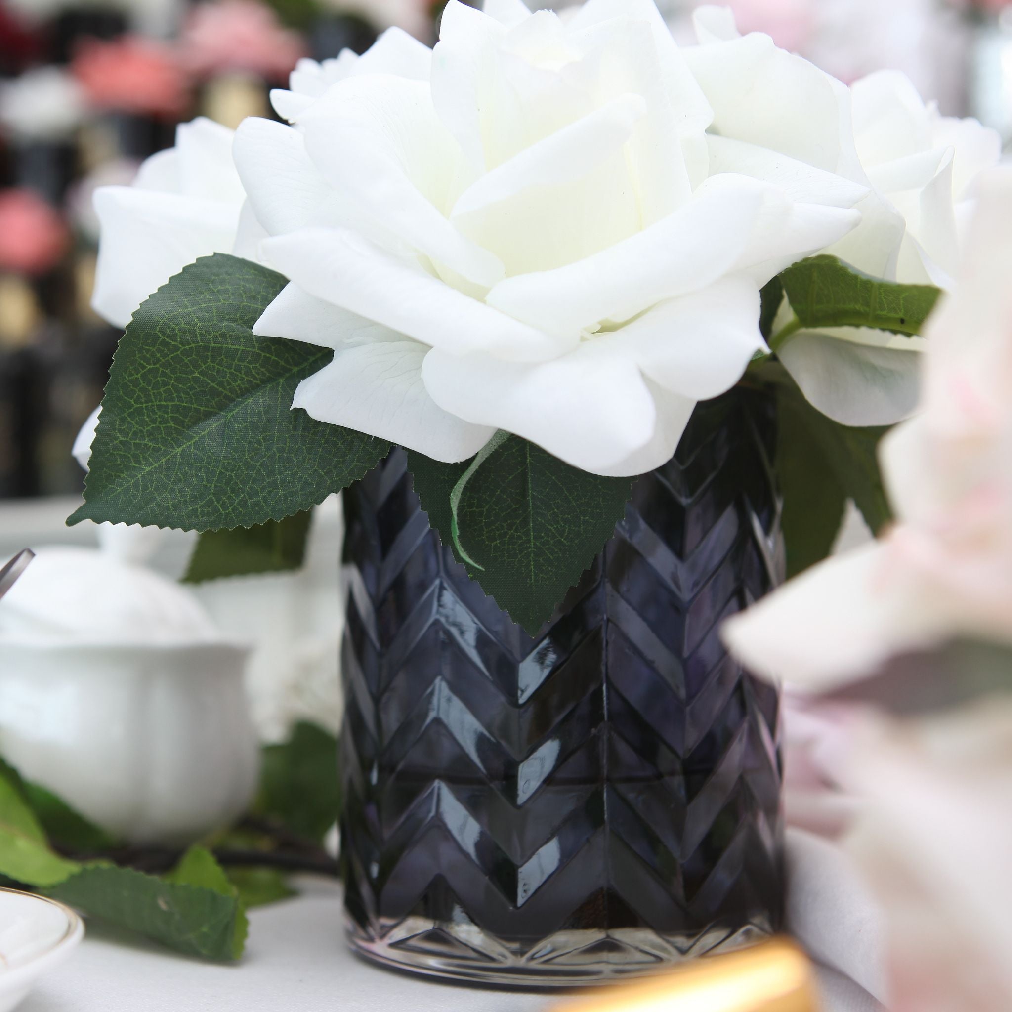 a herringbone vase with white flowers on a table
