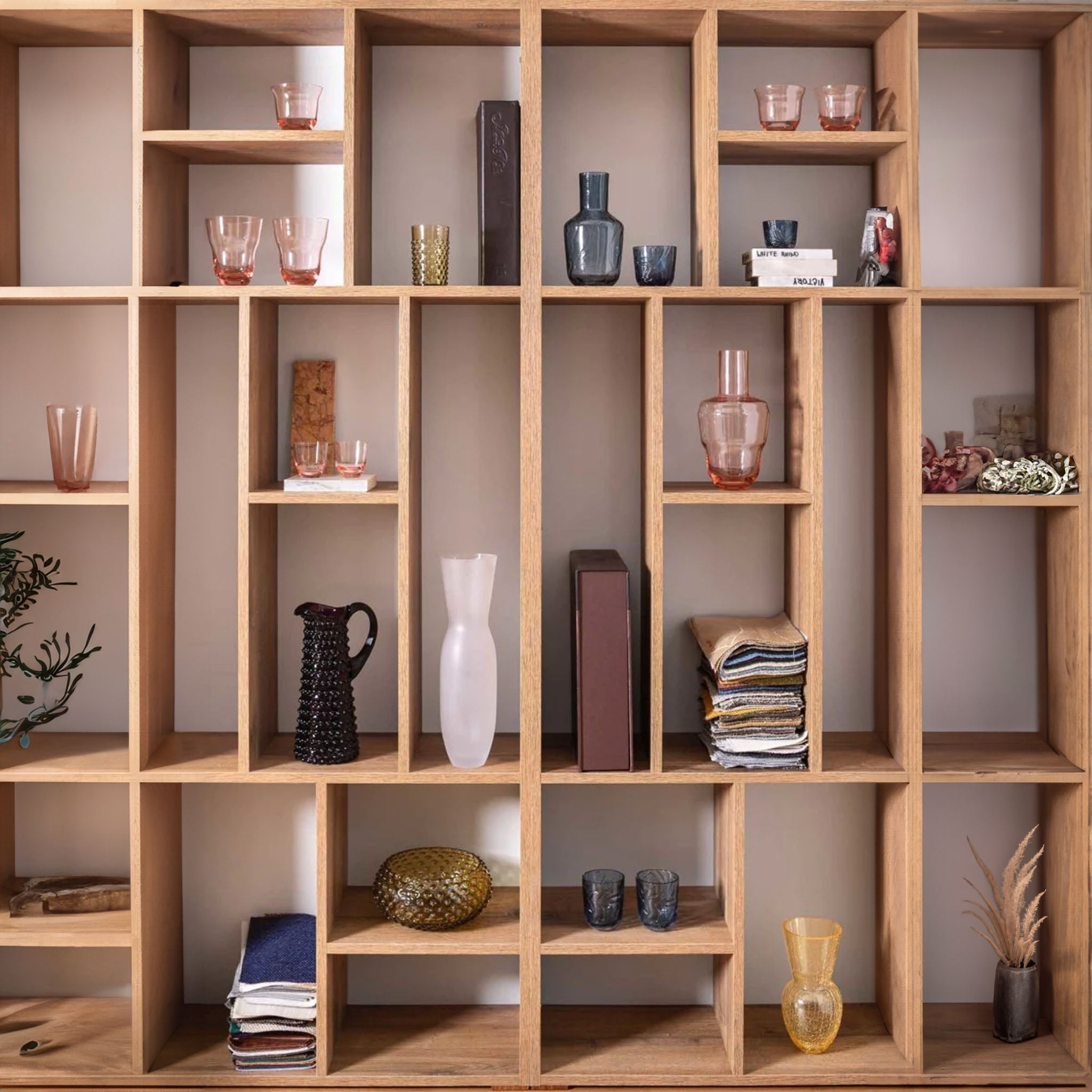 a wooden shelf filled with vases, pink glasses, and books