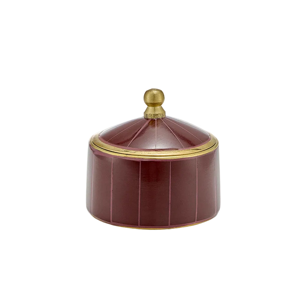 A small round lidded box in glossy deep burgundy with vertical fluted panels and gold trim, topped with a gold knob, shown on a plain light beige background.