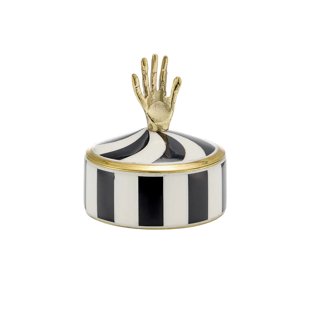 A small round lidded box with black and white vertical stripes, a gold rim, and a gold hand-shaped top handle, shown on a plain light background.