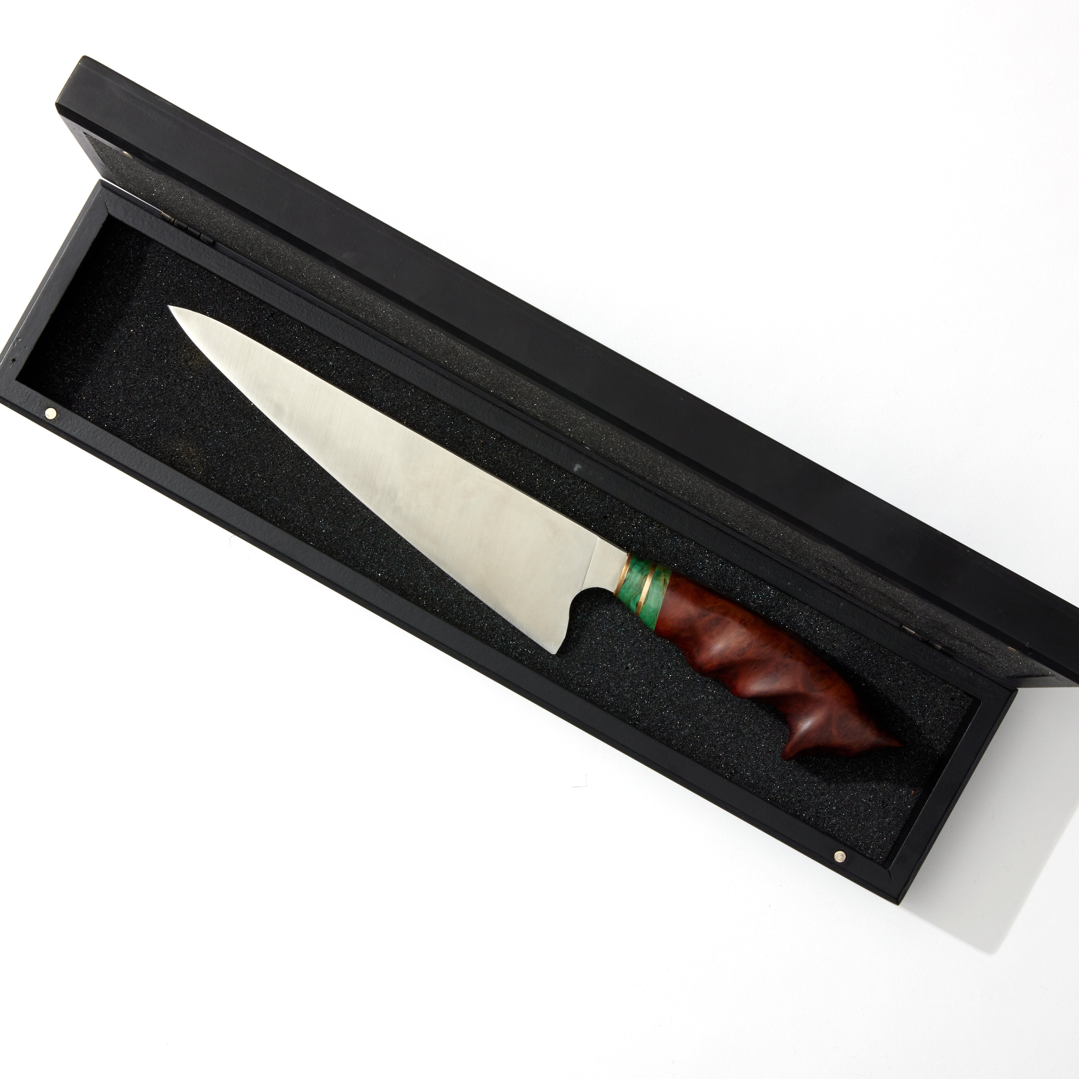 a knife in a black box with a wood handle on a white surface