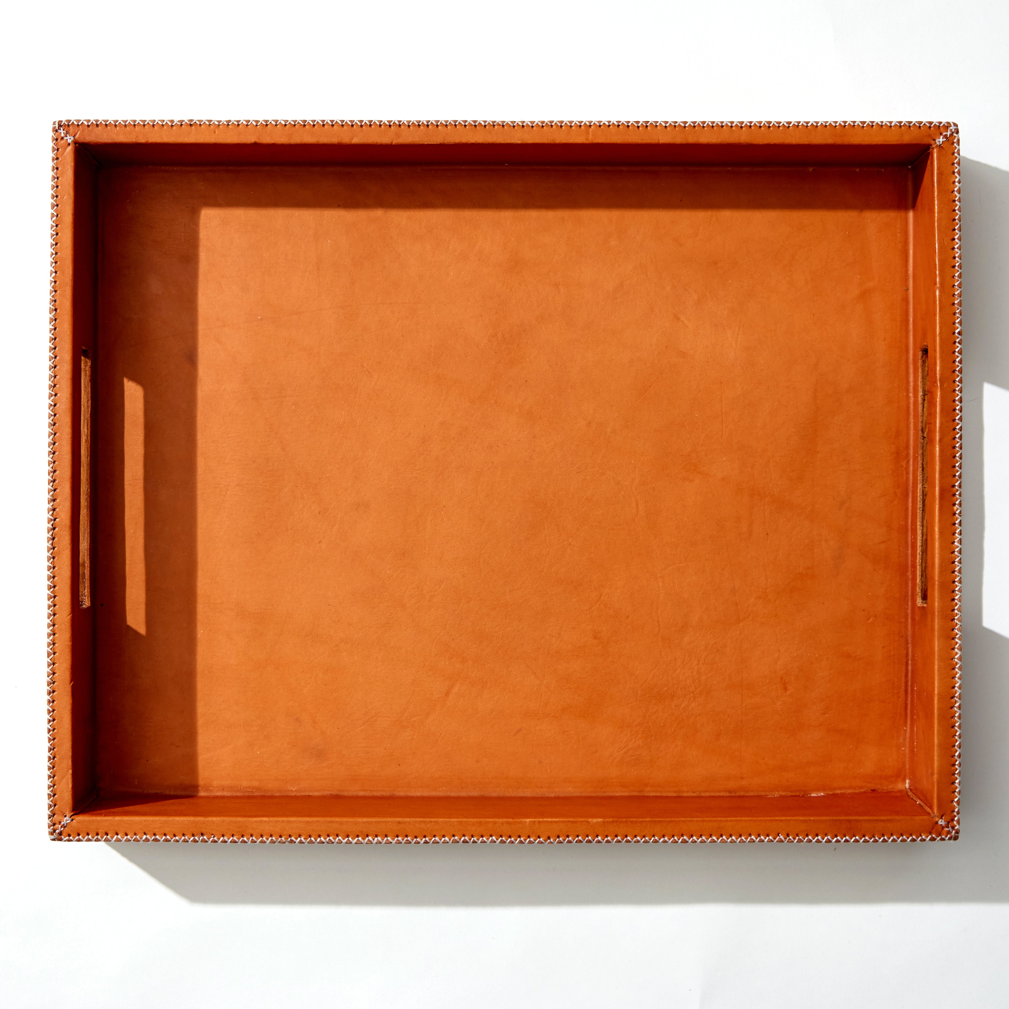 Over Head Photo of Our Large Tan Leather Tray With Hand Stitched White Thread. Handles Are Rectangle Cut Outs On Each Side.