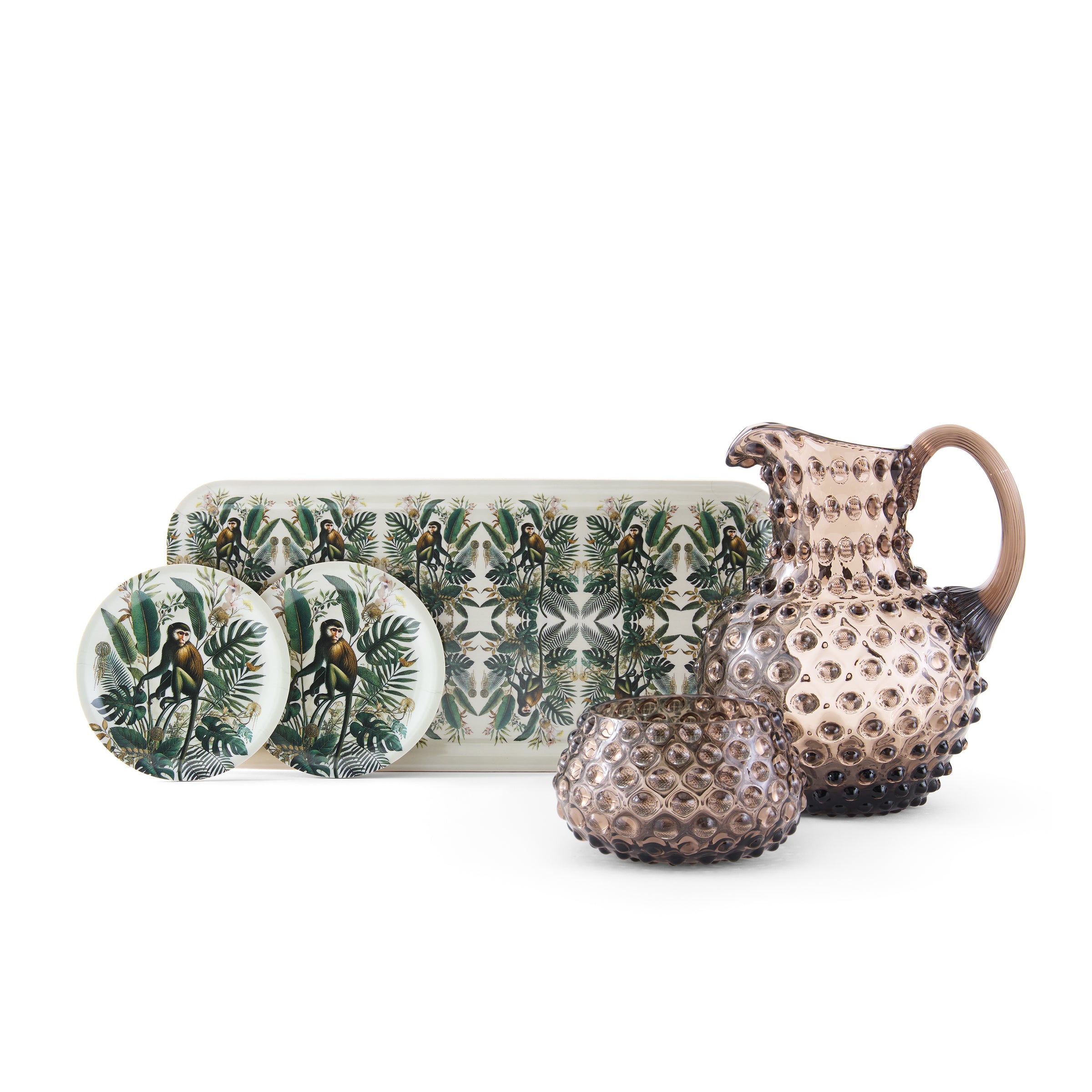 Ceramic pitcher and plates with a jungle-themed design on a white background