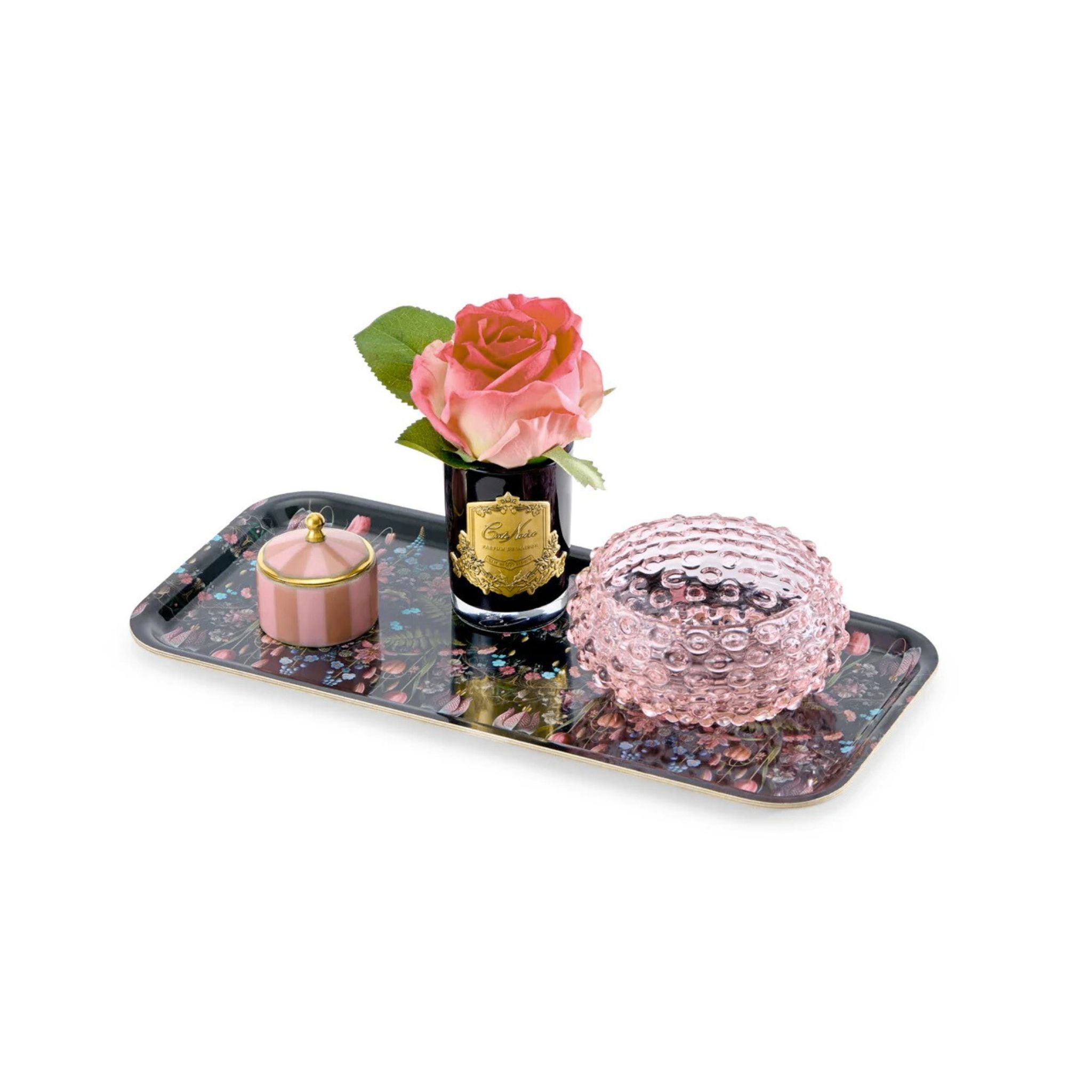 Decorative tray with a bottle, pink rose, and decorative ball on a white background