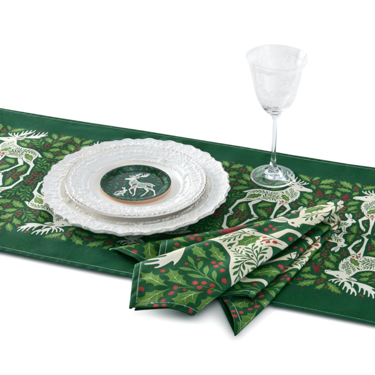 Table setting with green table runner, white plates, and napkins featuring deer and holly design.