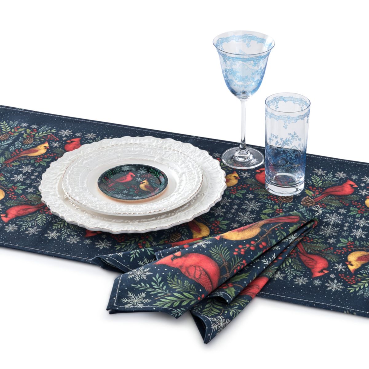 Table setting with decorative placemat, plates, and glasses featuring winter-themed design.
