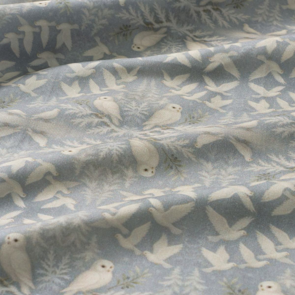 Fabric with a pattern of white birds and trees on a blue background