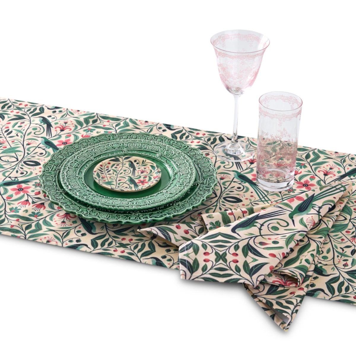 Decorative table setting with green plates and glasses on a patterned tablecloth.
