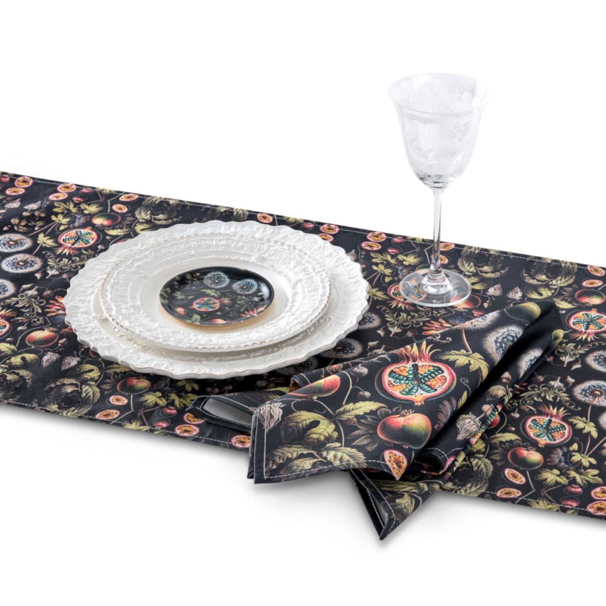 Table setting with floral patterned table runner, plates, and napkin on a white background