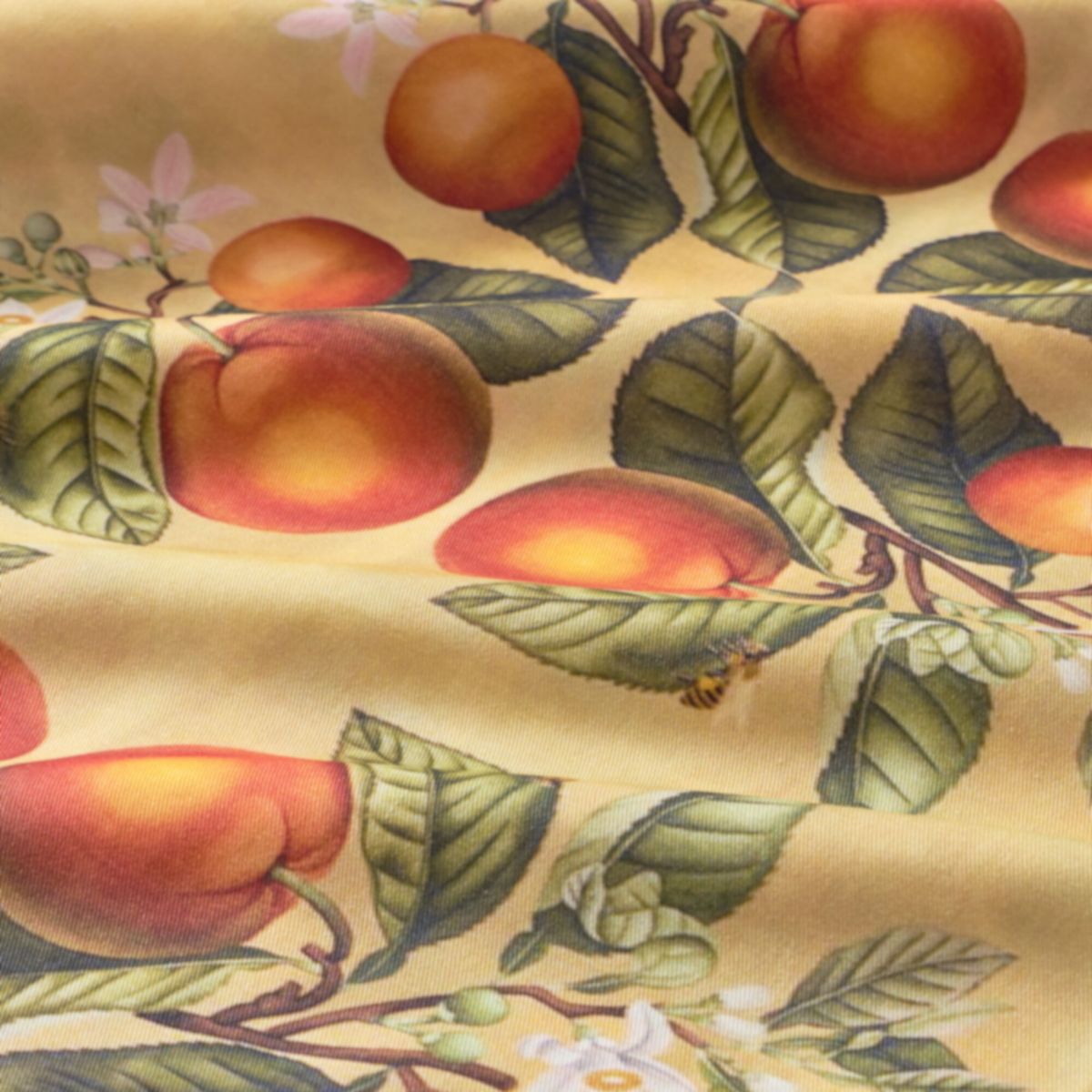 Fabric with a pattern of peaches, leaves, and flowers on a yellow background