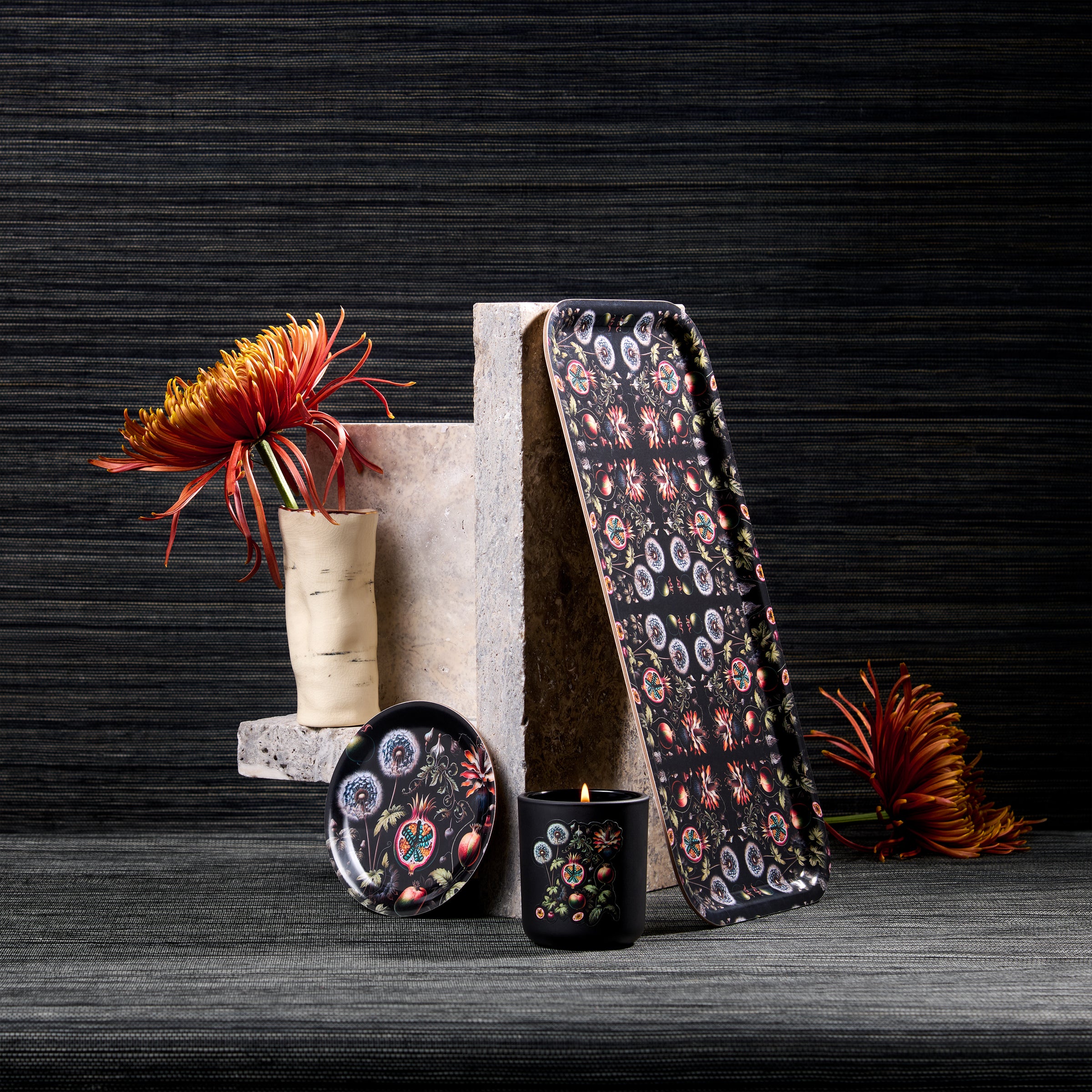 Decorative items including a vase with flowers, books, and a patterned tray on a dark surface.
