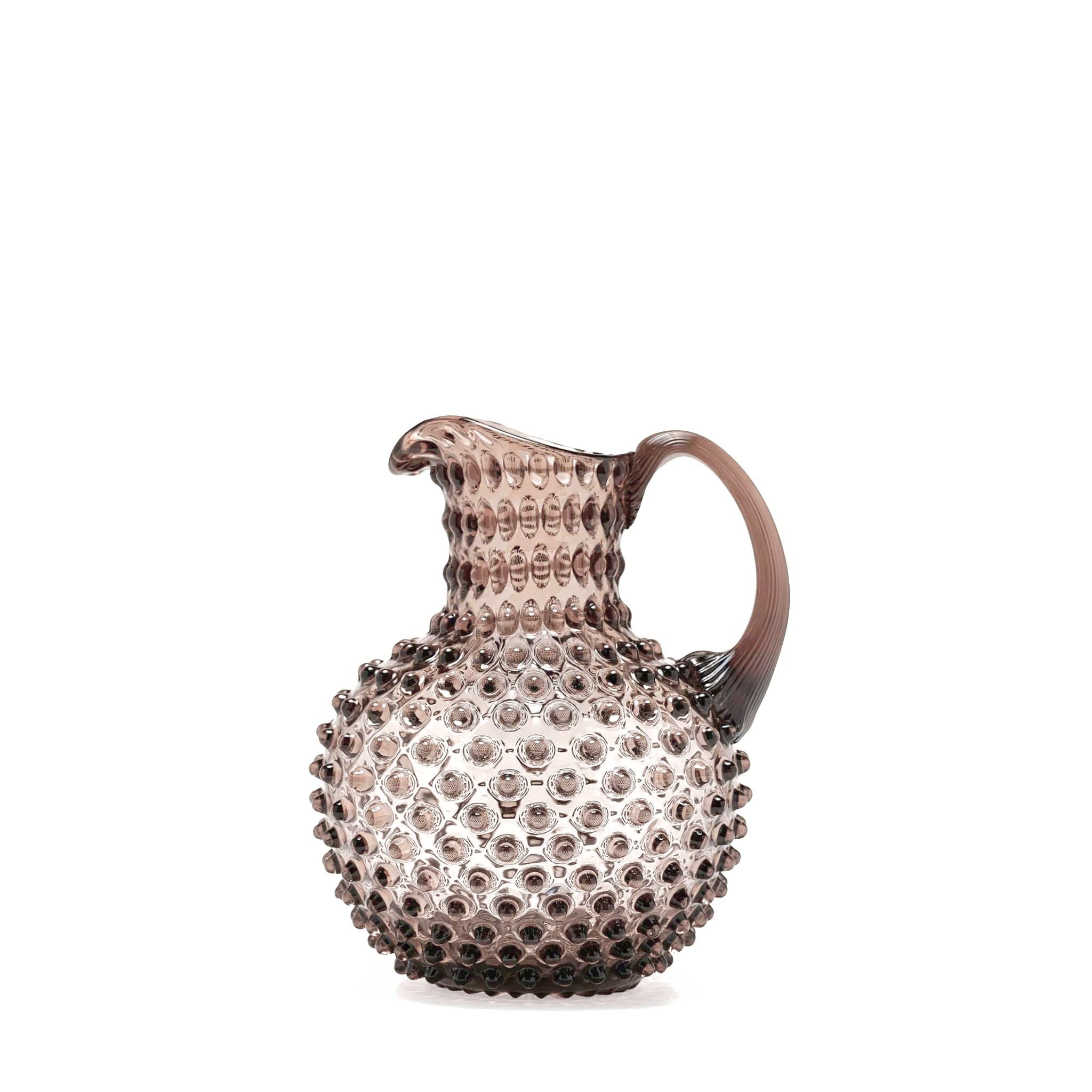 Decorative glass pitcher with textured surface on a white background