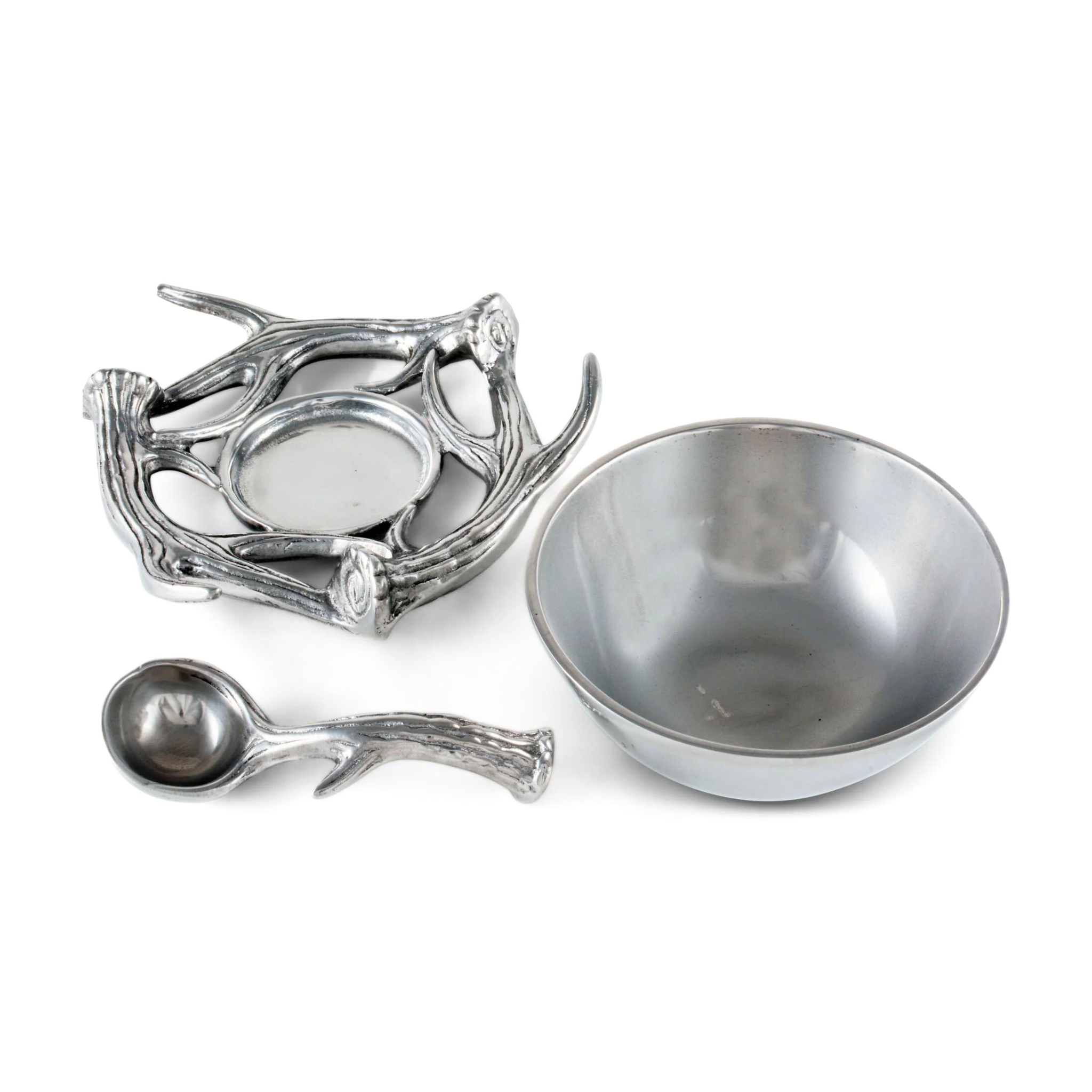 an aluminum serving bowl with antler base and spoon laid out rest on a white surface