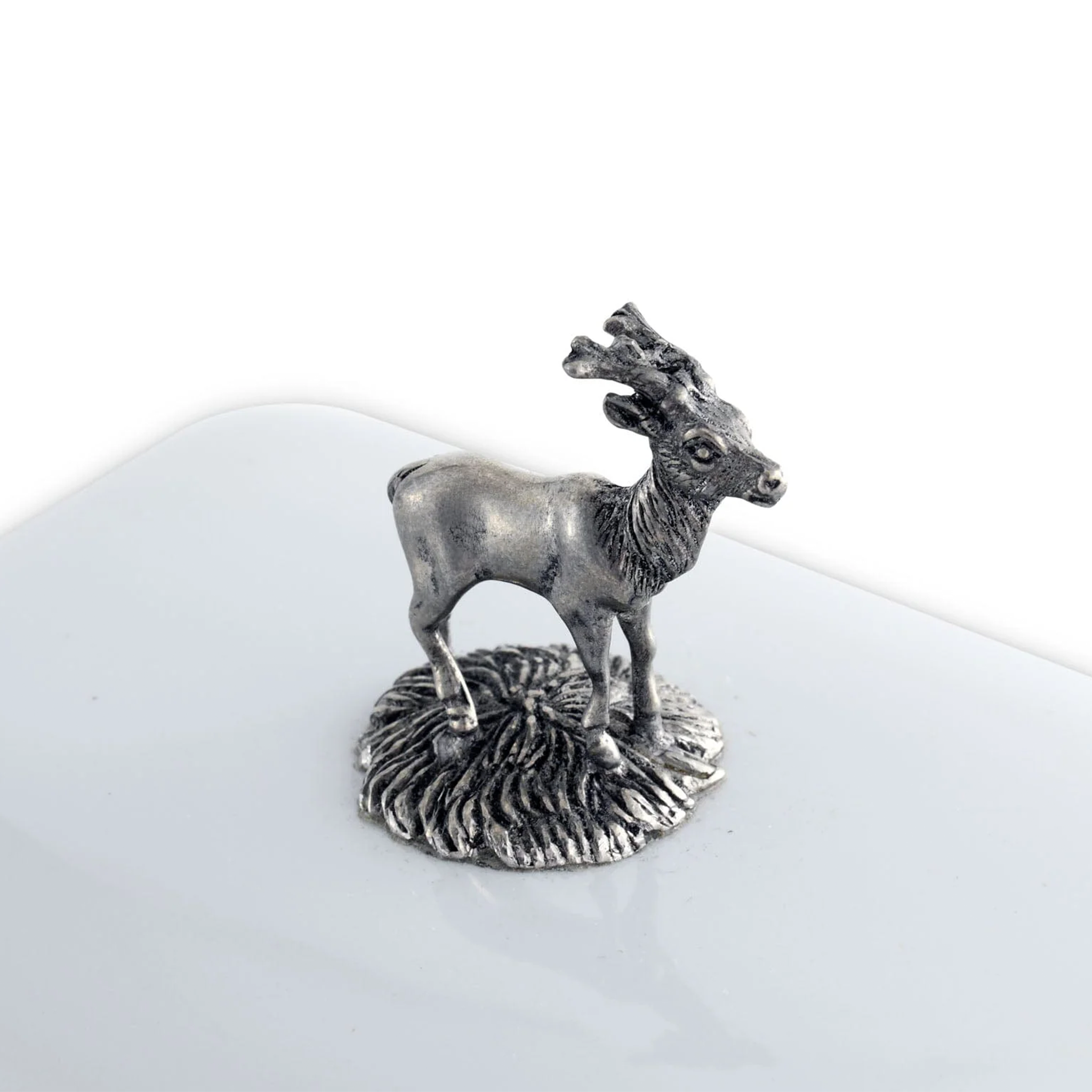 a pewter stag figure on top of a w white butter dish