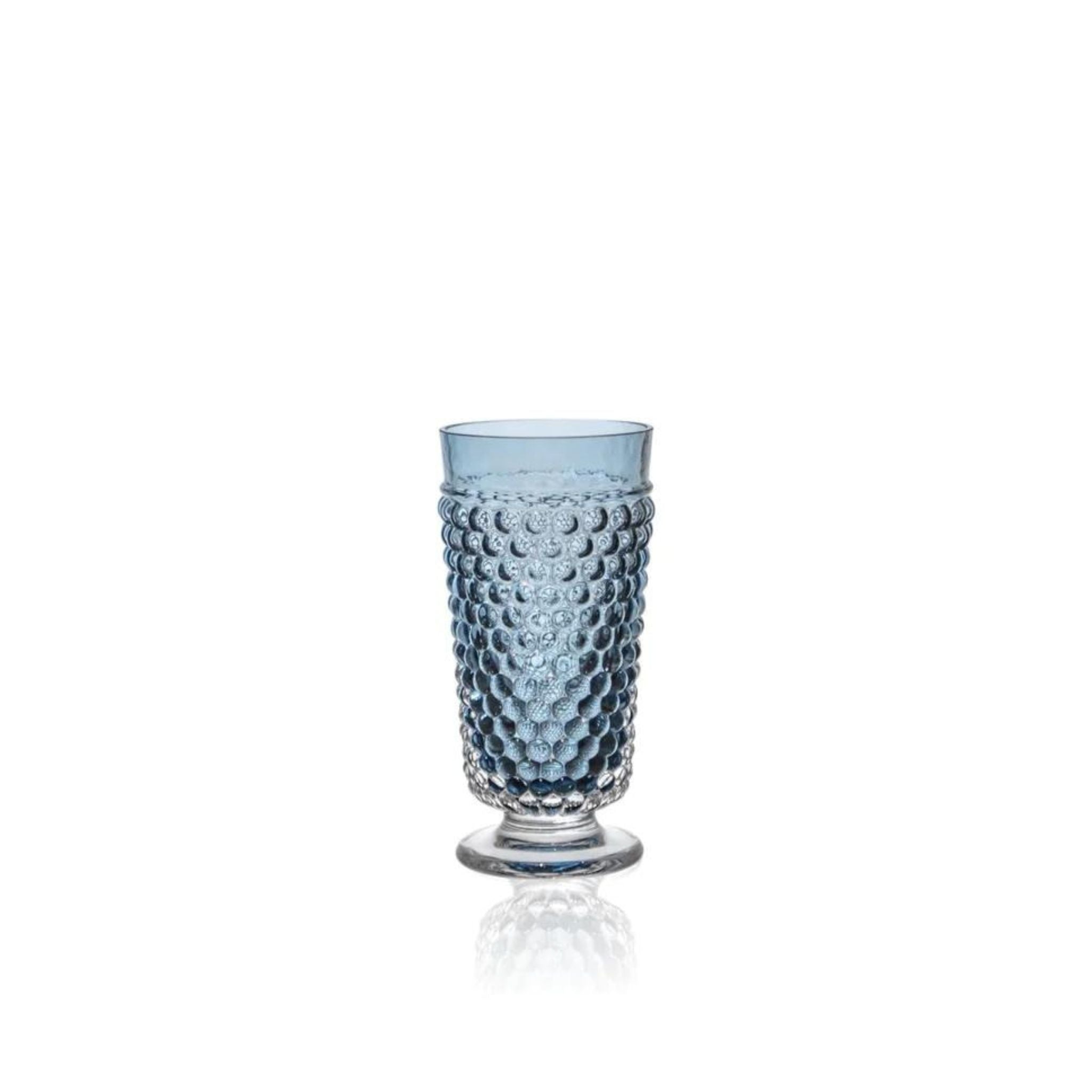 a blue hobnail glass is sitting on a white surface