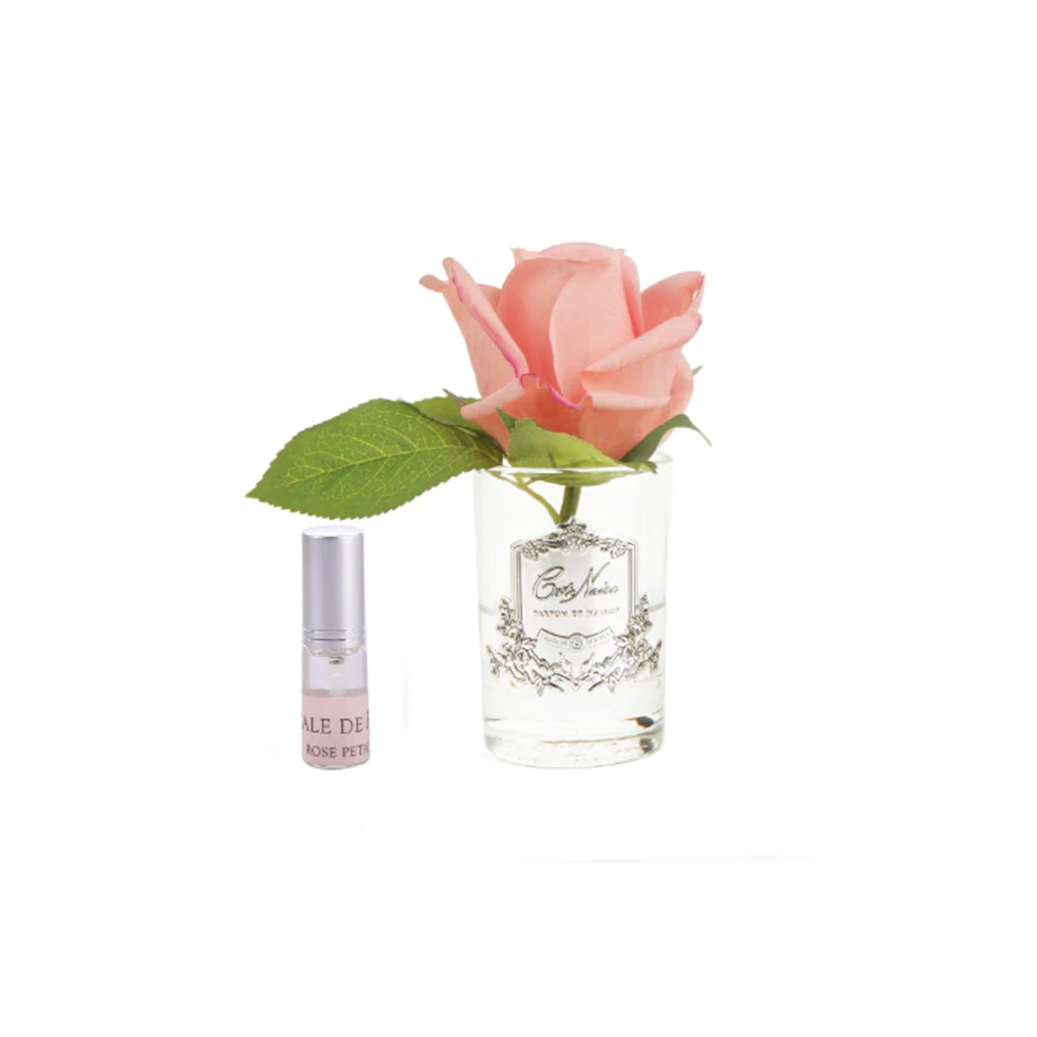 a pink rose in a glass vase next to a bottle of fragrance