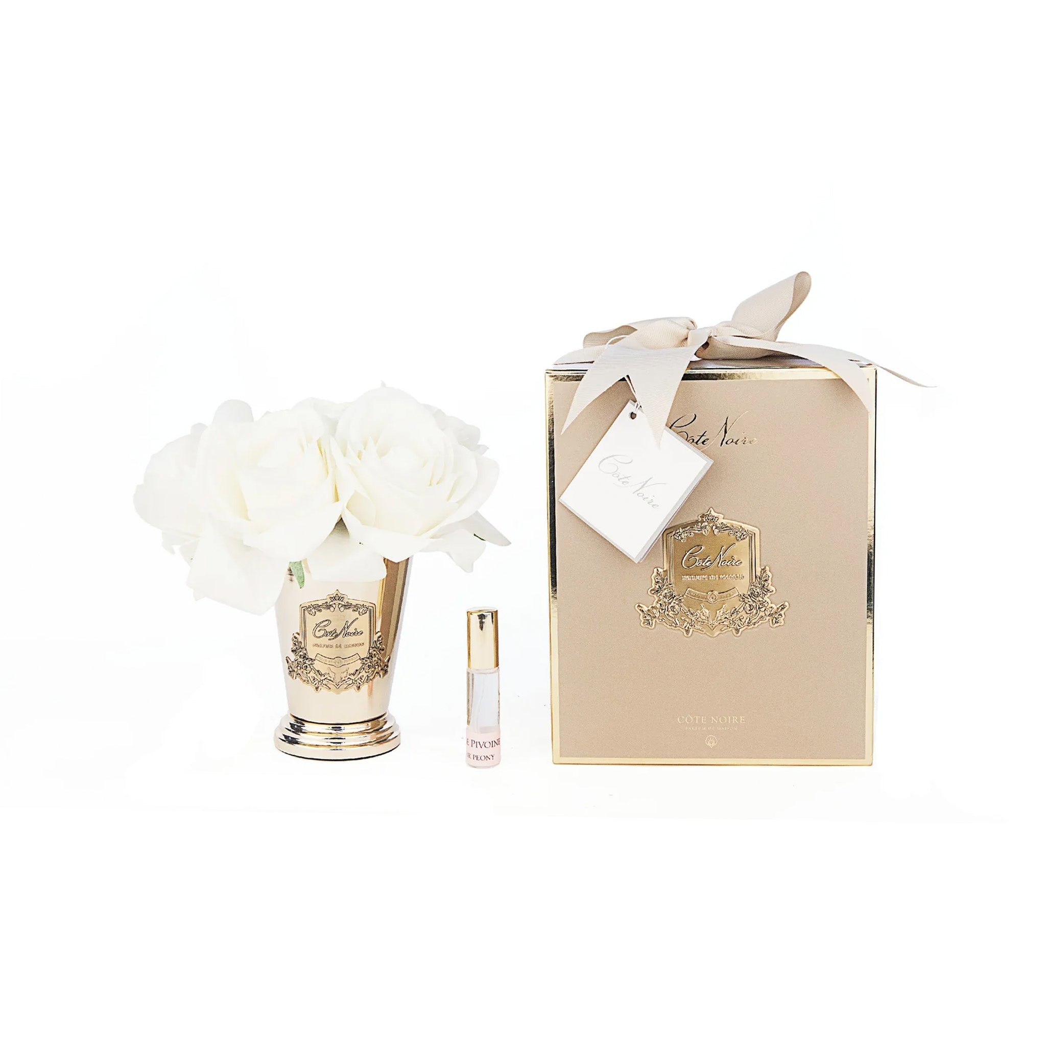 a bottle of perfume next to a gold vase with flowers by cote noire