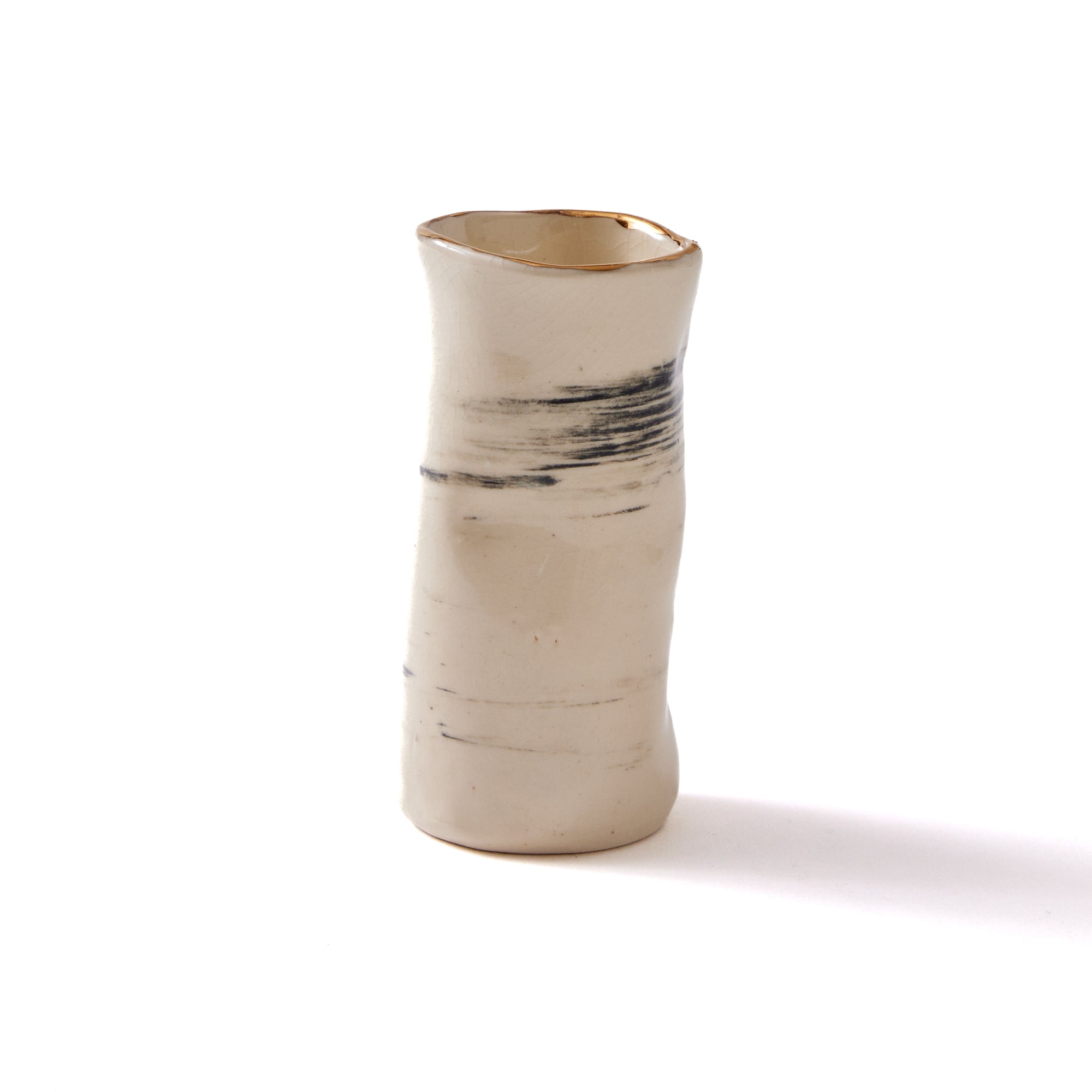 a handmade clay bud vase that resembles birch bark with gold detailing sitting on top of a white table