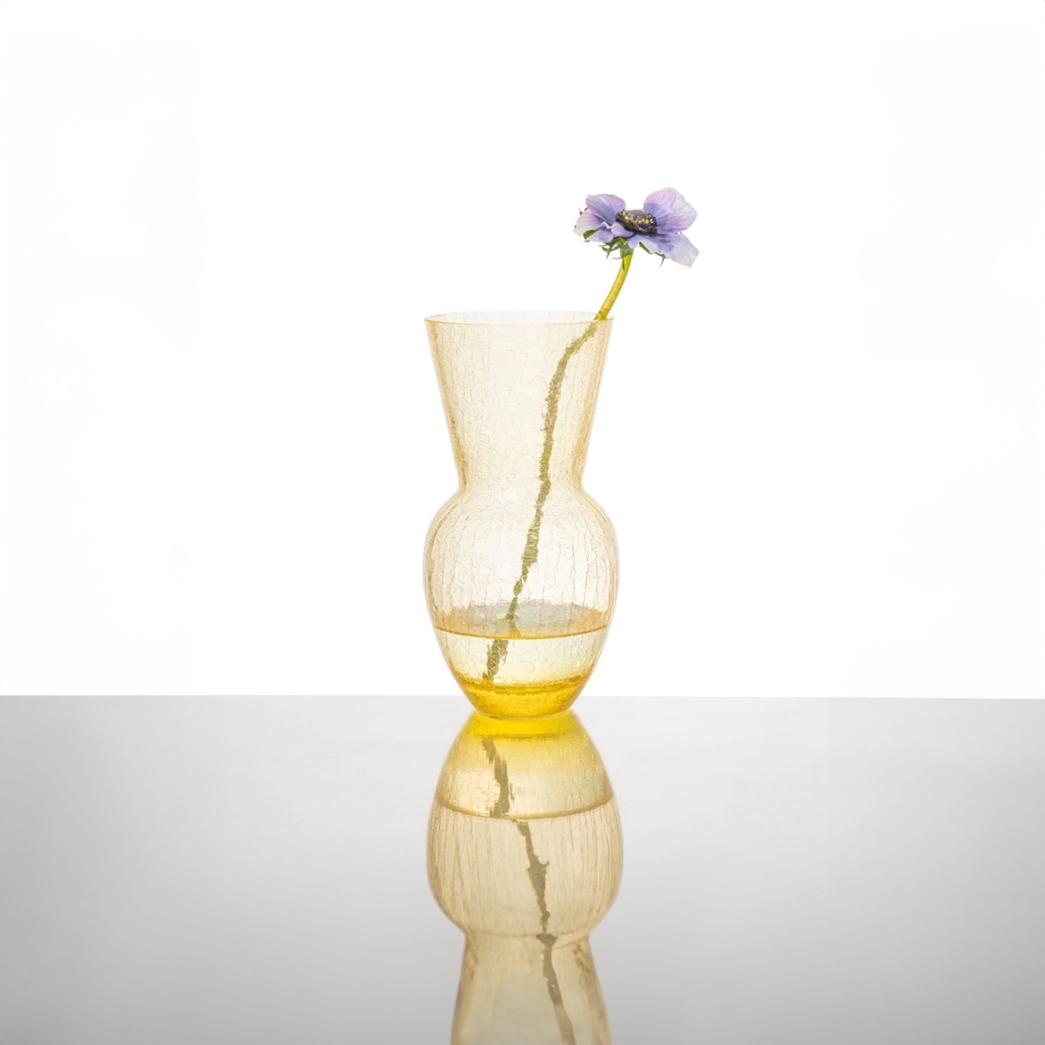 a yellow vase with a purple flower in it