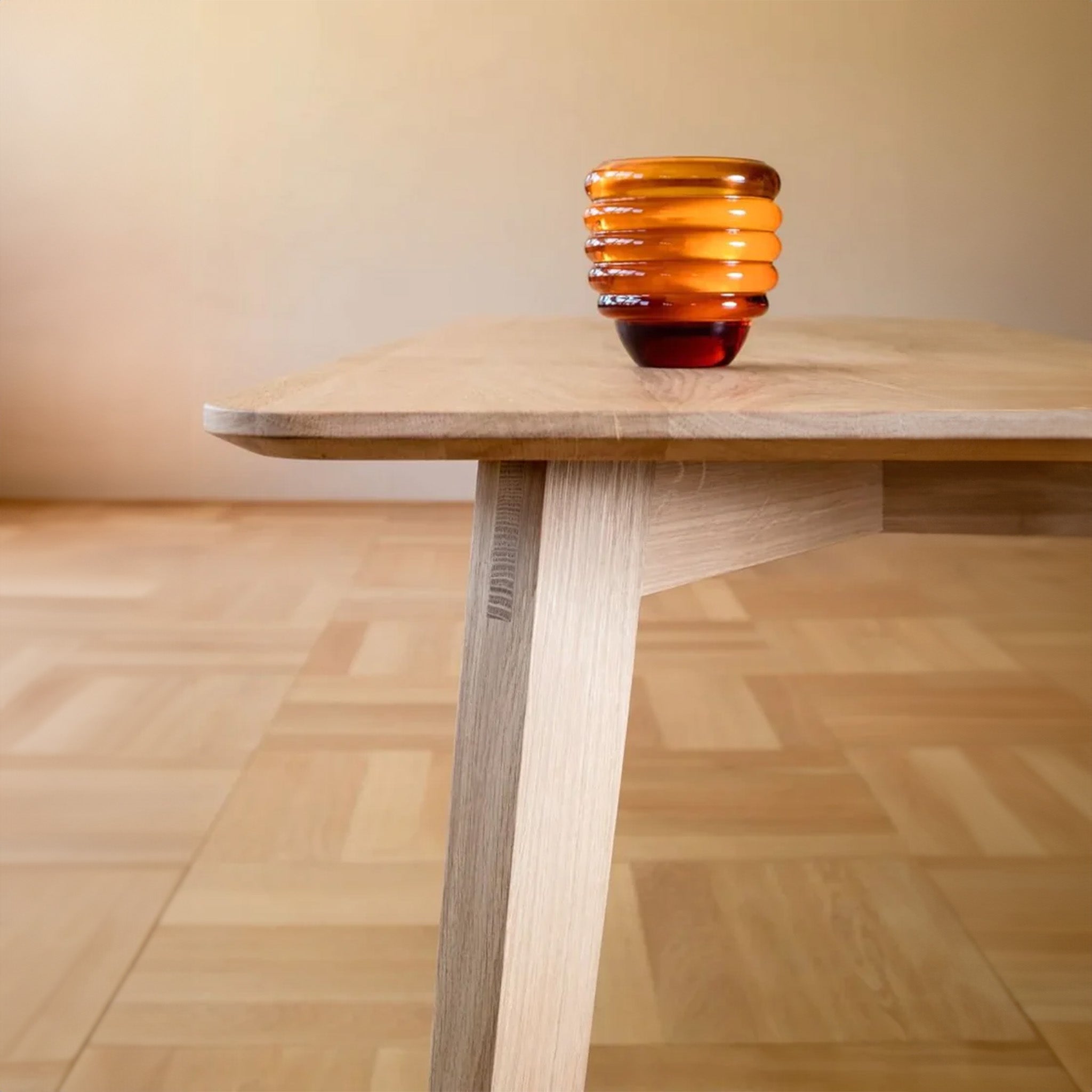 a glass amber candle  sitting on top of a wooden table