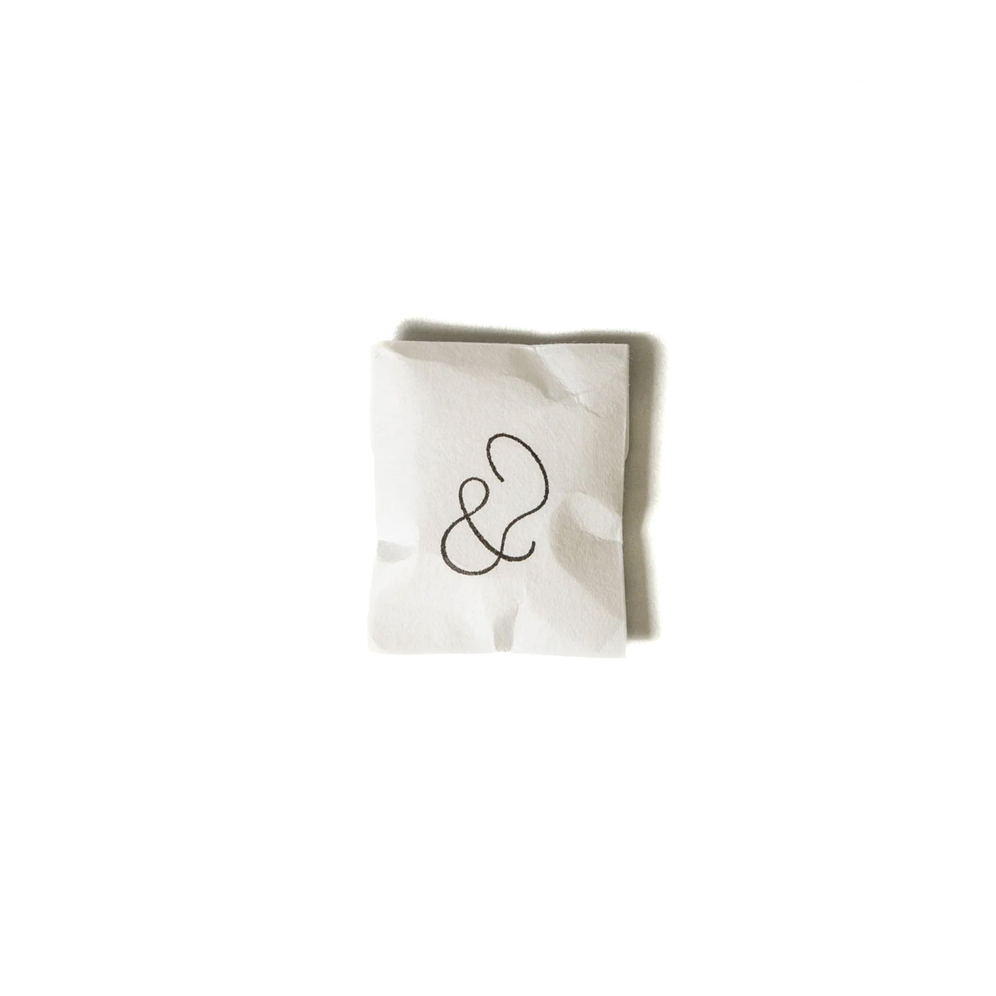 Minimalist white packaging with an elegant ampersand symbol, containing a brass incense holder.