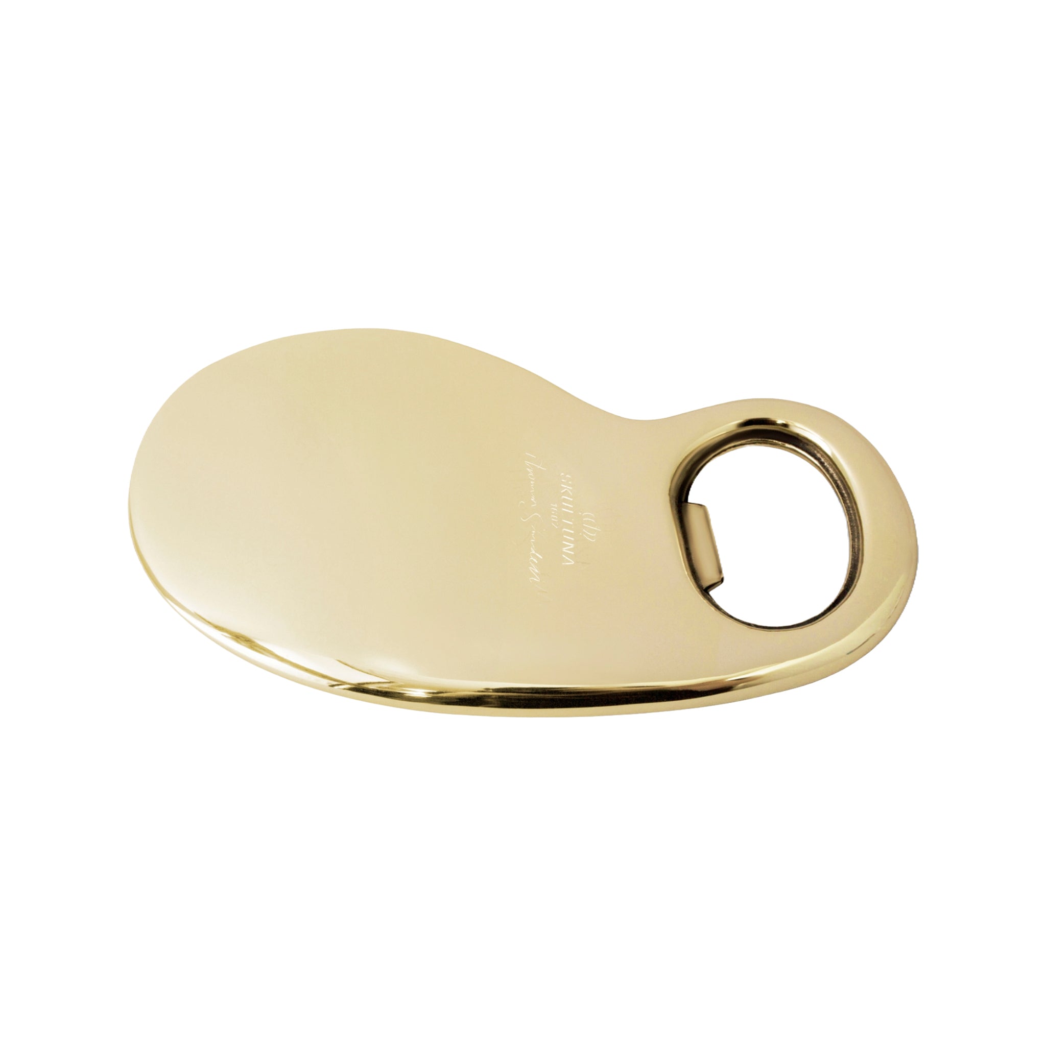 A sleek, gold-colored bottle opener with a fluid, kidney-shaped design and a circular opening on one end. Engraved on its surface is the text 'Skultuna 1607', indicating the brand and its founding year. The bottle opener is presented on a white background, with a reflective surface that accentuates its metallic sheen and elegant curves.