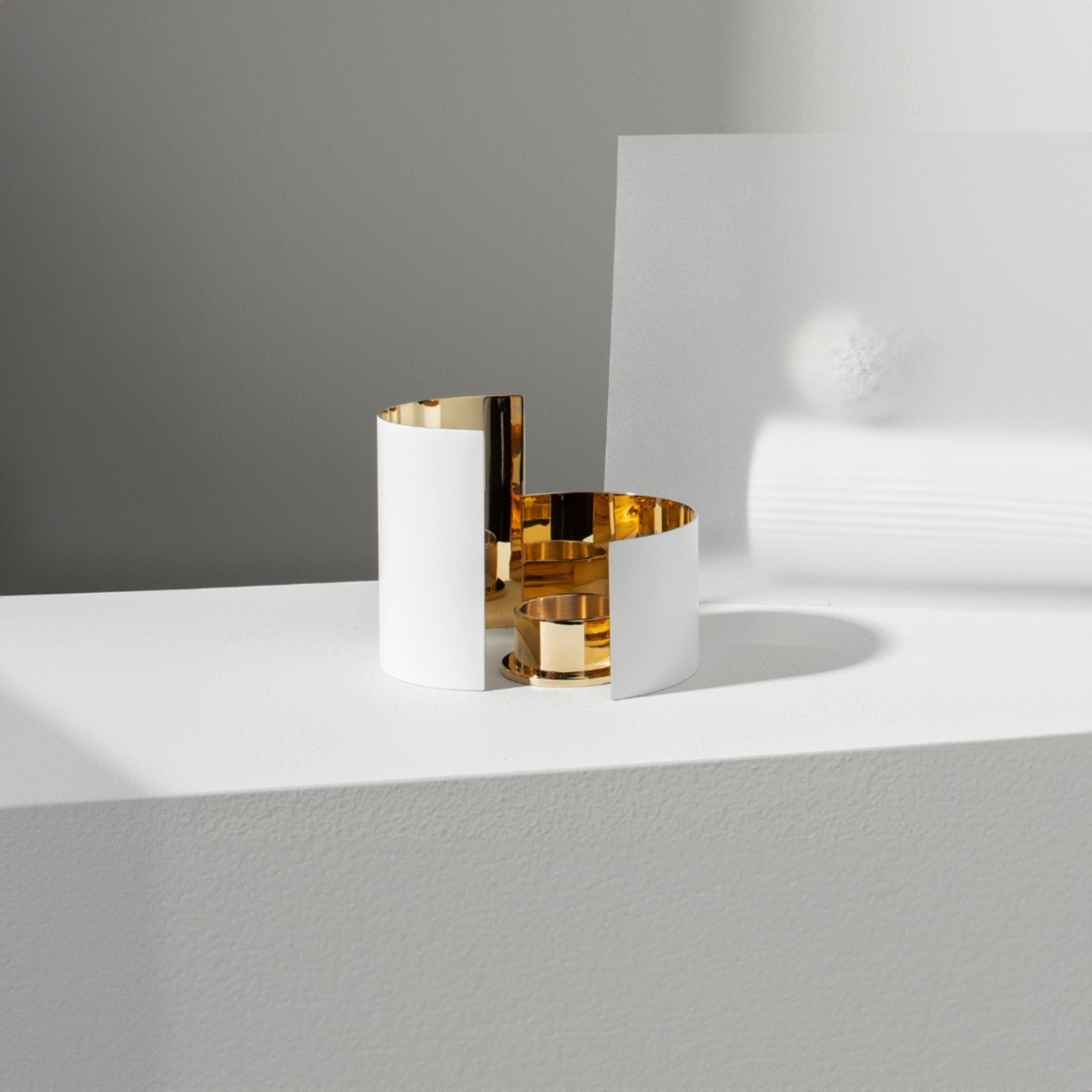 a white table with a white and brass infinity candle holder by skultuna