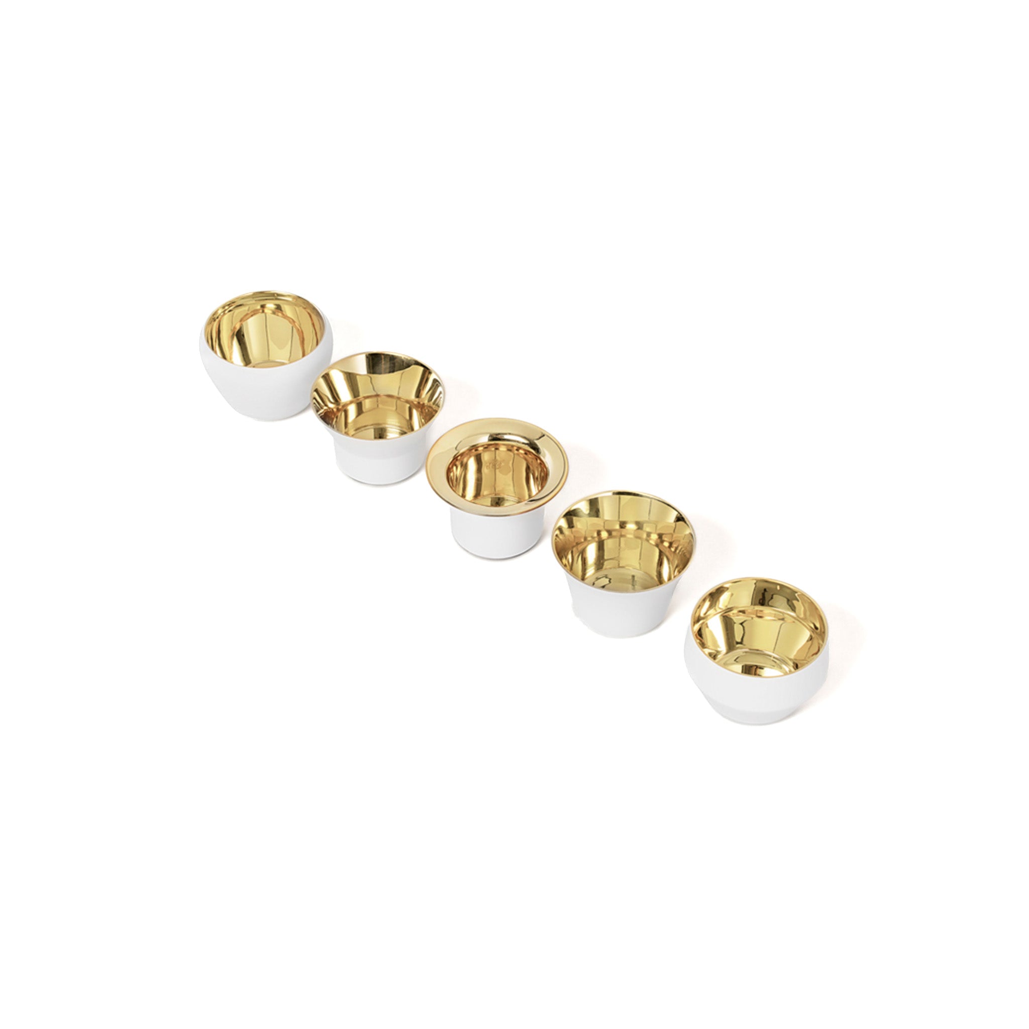 a set of five white and brass tealights by skultuna at a diagonal on a white background