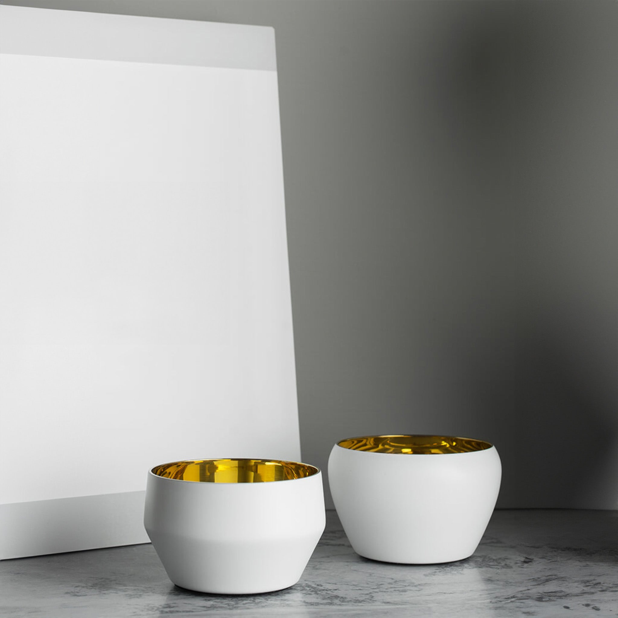 a couple of  white and brass tealights by skultuna sitting on top of a table