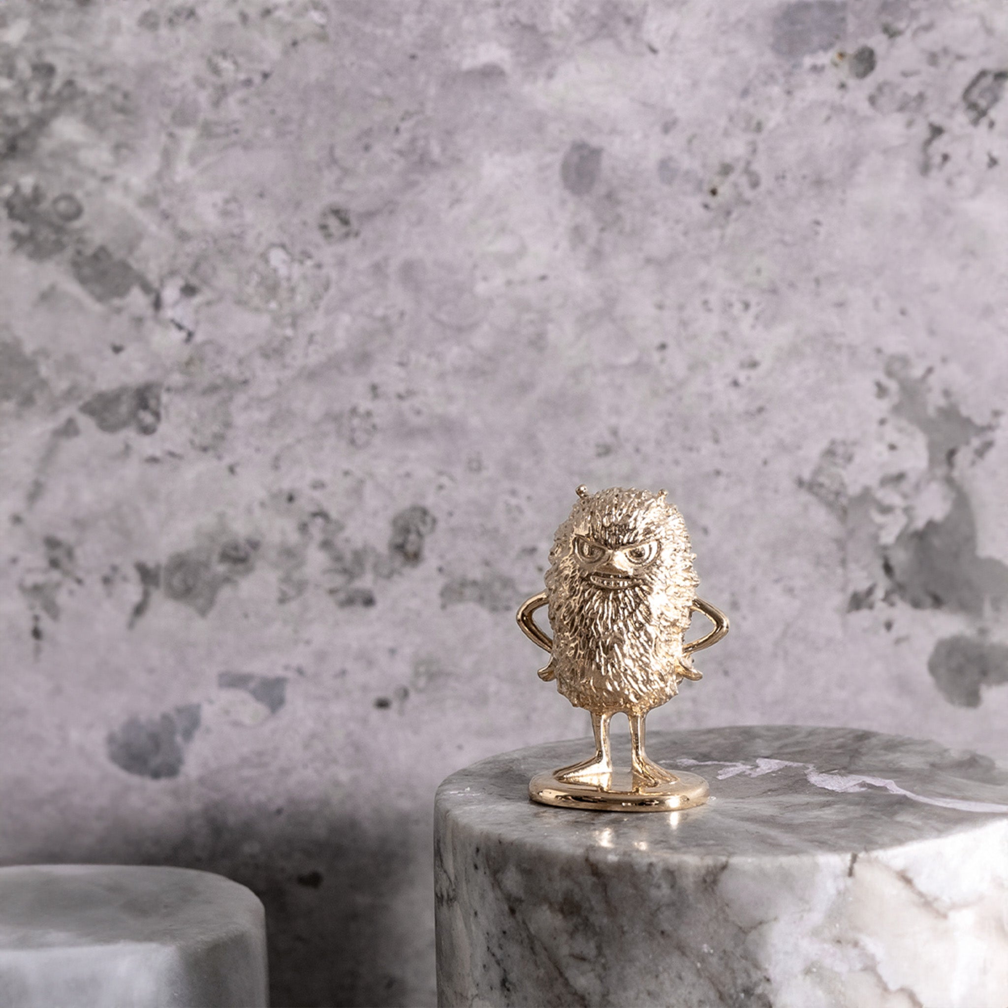 a gold figurine of moomin stinky sitting on top of a marble table
