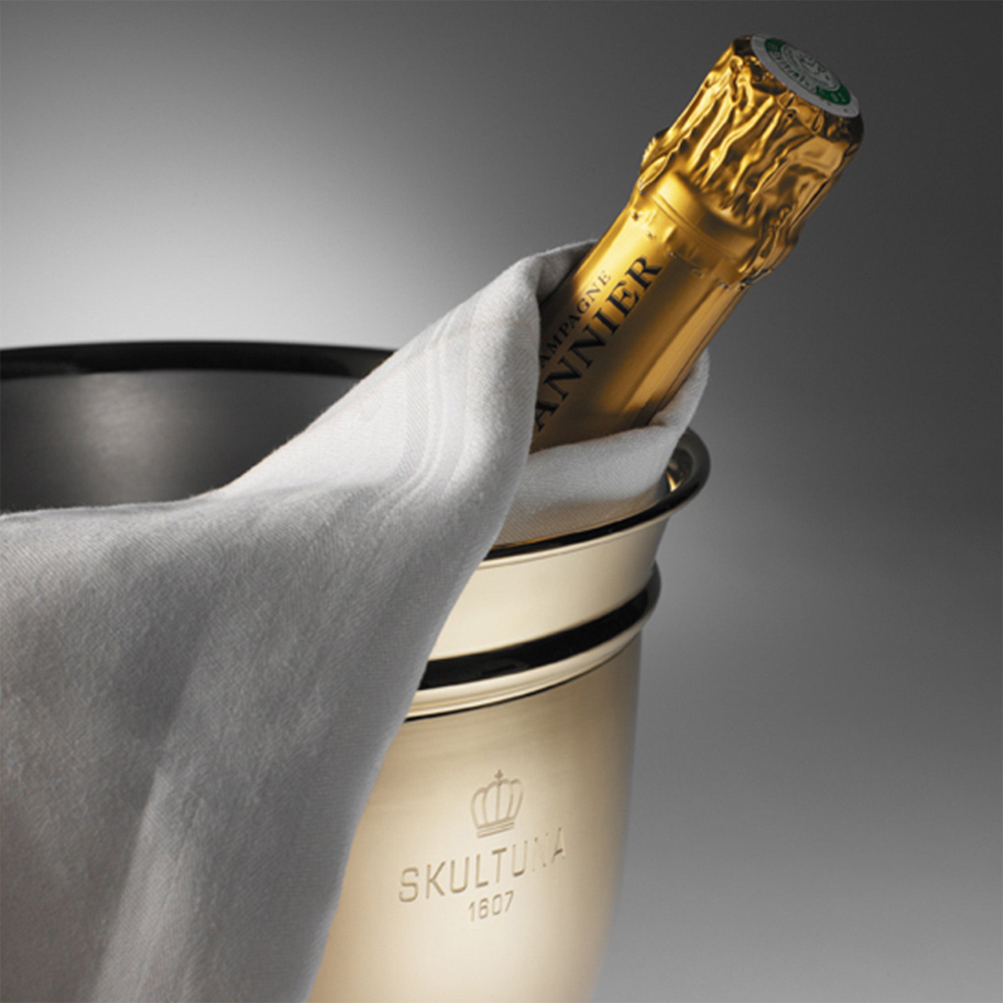 a bottle of champagne sitting in a brass champagne and wine cooler 