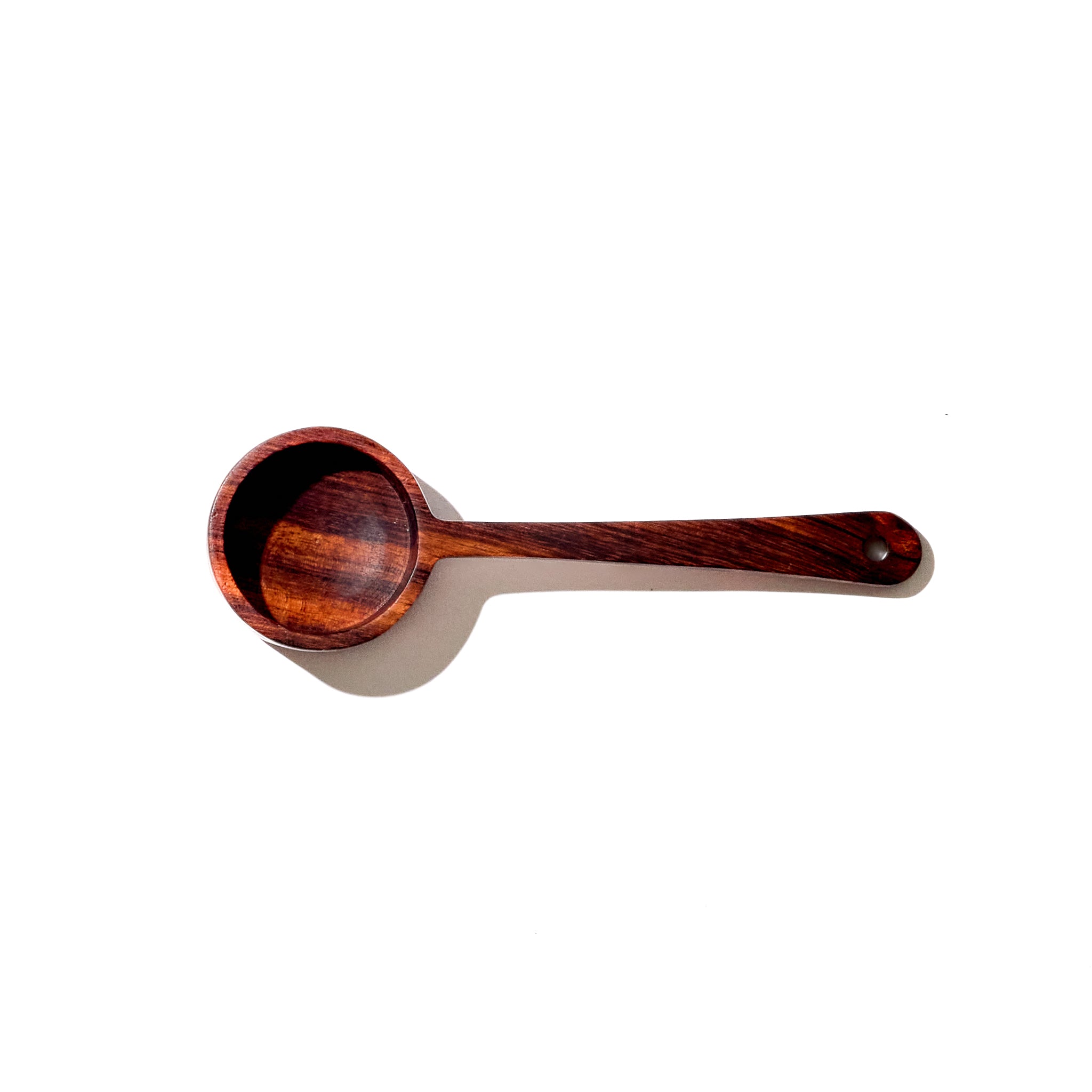 a wooden coffee scoop sitting on top of a white surface