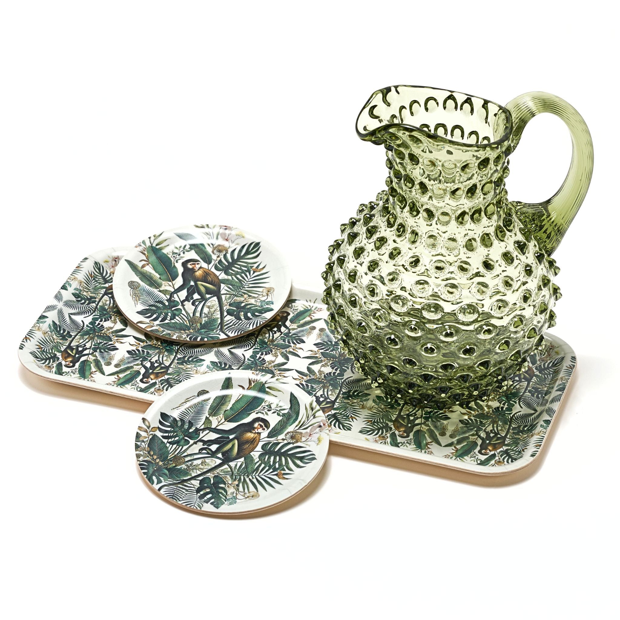 Green ceramic pitcher and coasters with nature-themed design on a white background