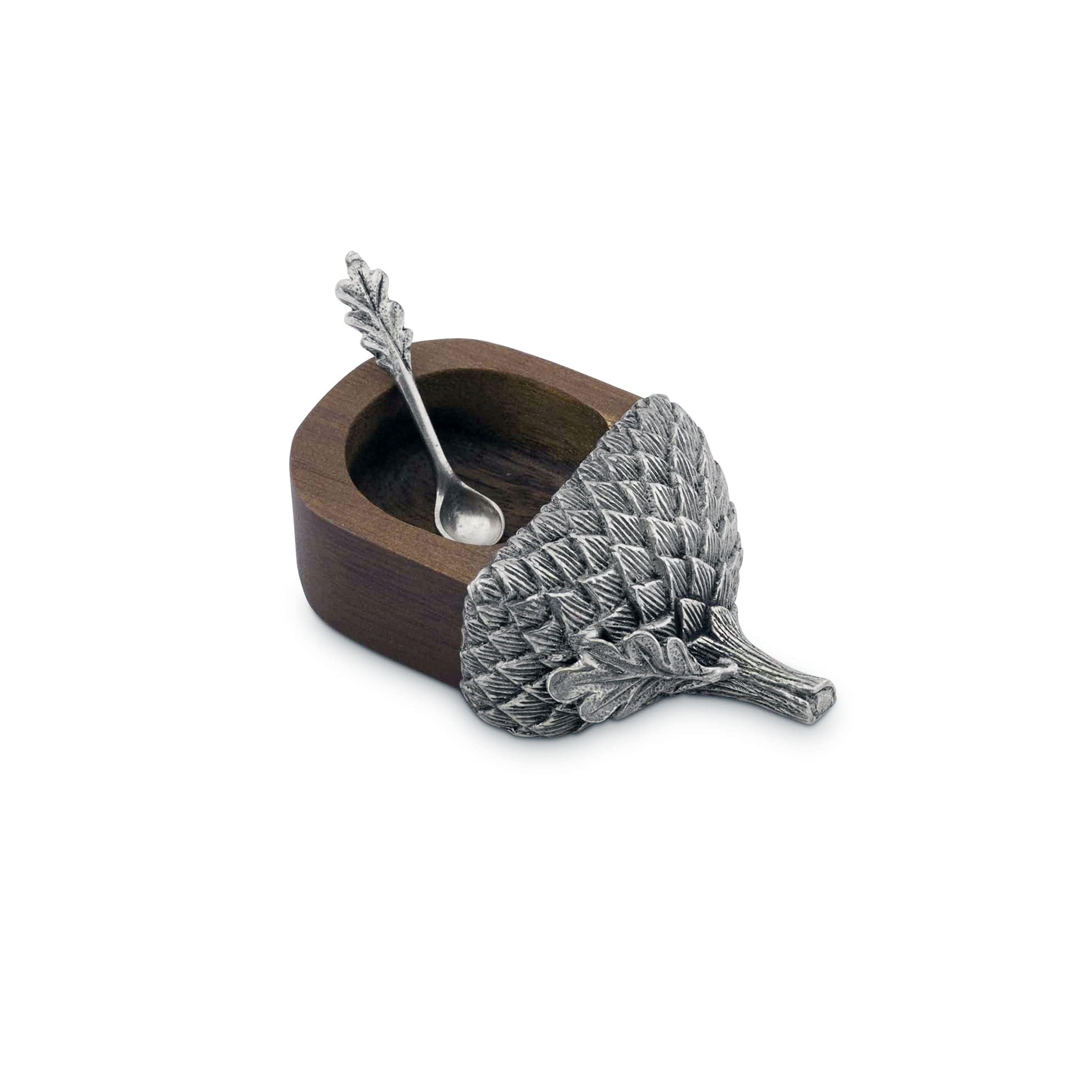 a small wooden acorn salt cellar with a silver spoon in it with a pewter cap on it on a white background