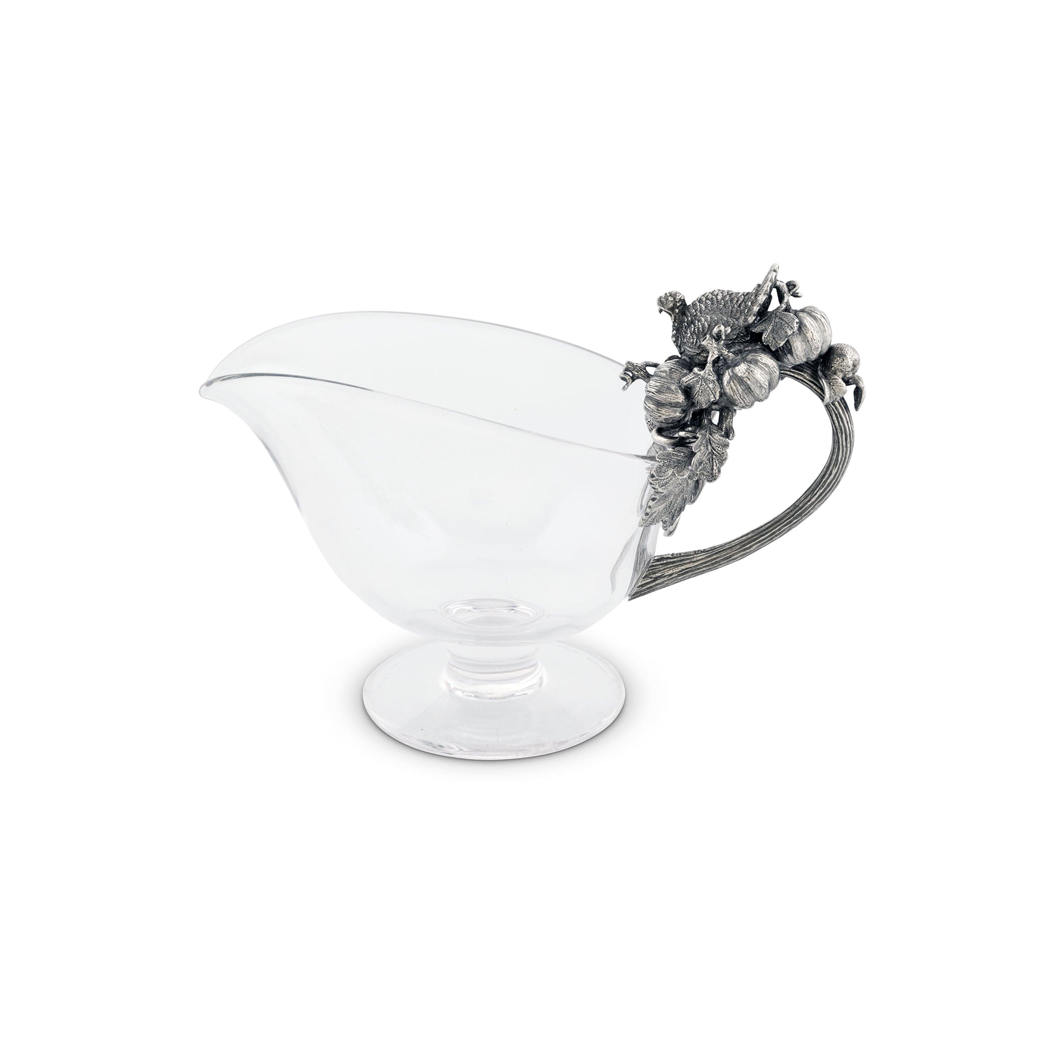 a side view of a glass gravy boat with pewter handle adorned with noble symbols of autumn's abundance