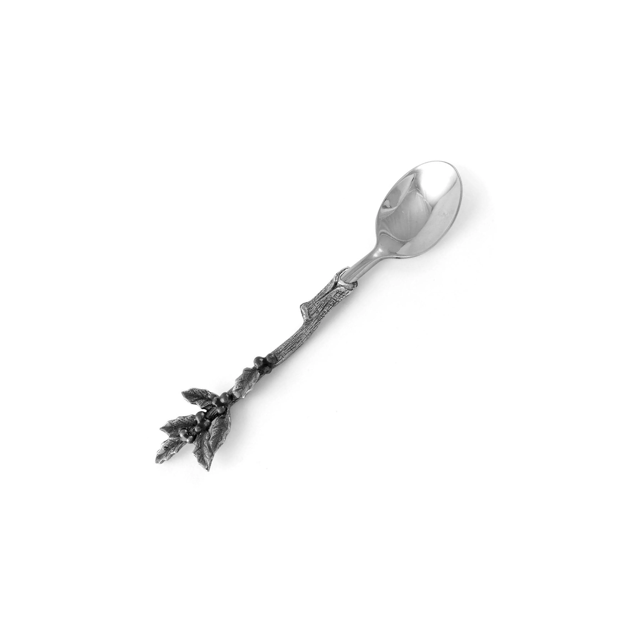 a polished pewter teaspoon with a handle ornately designed to resemble a holly branch, complete with leaves and berries, against a plain background
