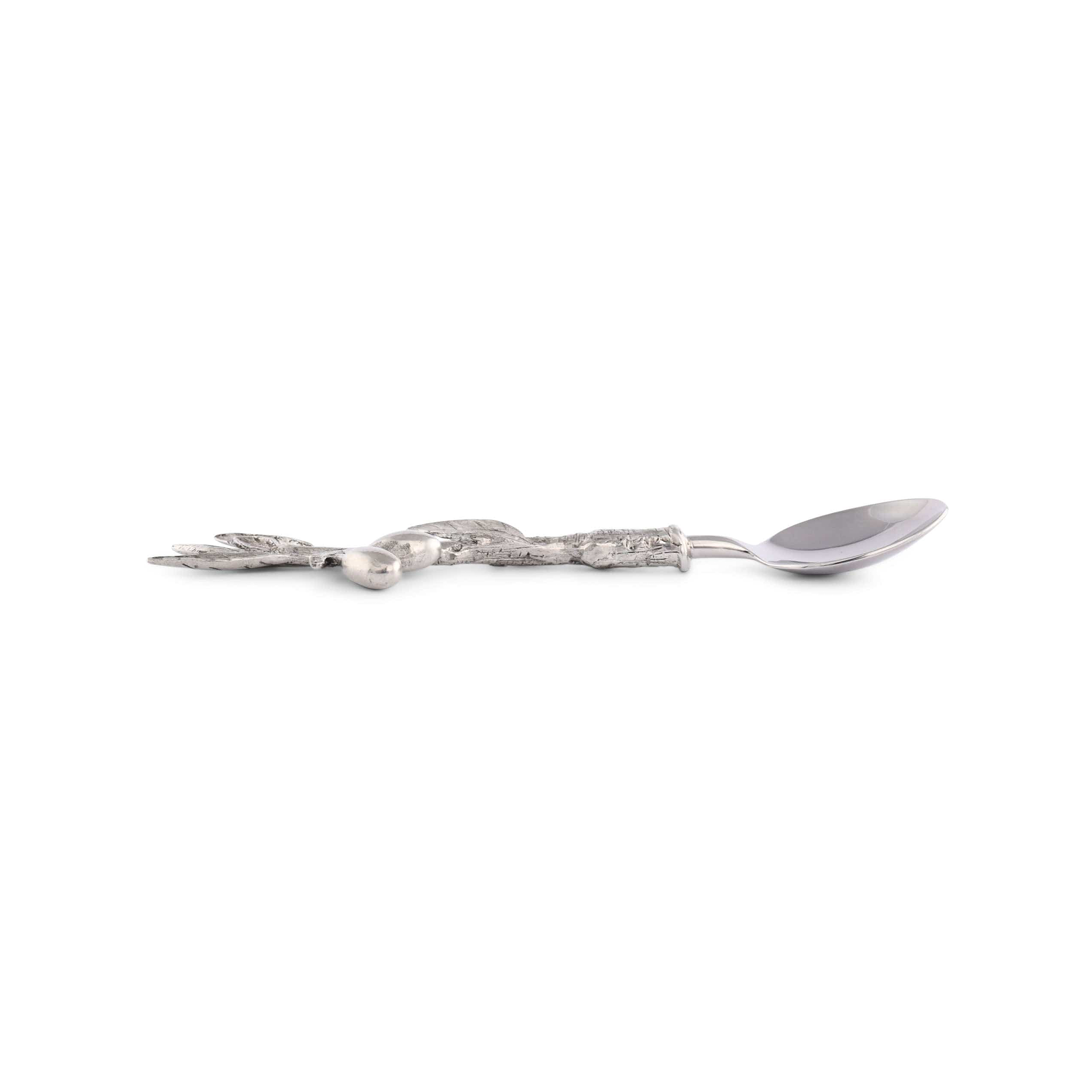 a spoon with olive branch design resting on a white surface