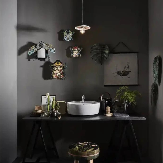 a bathroom with black walls and a white sink featuring a group of bug decor on the wall