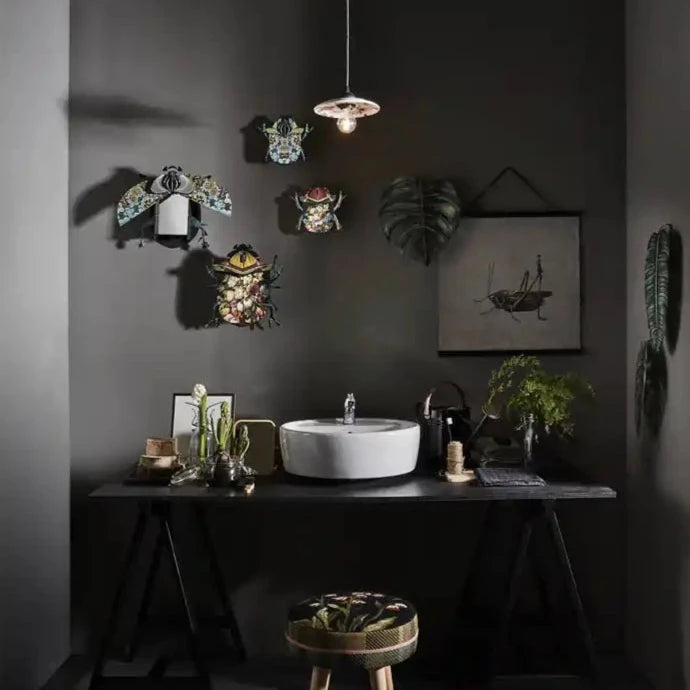 a bathroom with black walls and a white sink with a group of decorative beetles hanging on the wall